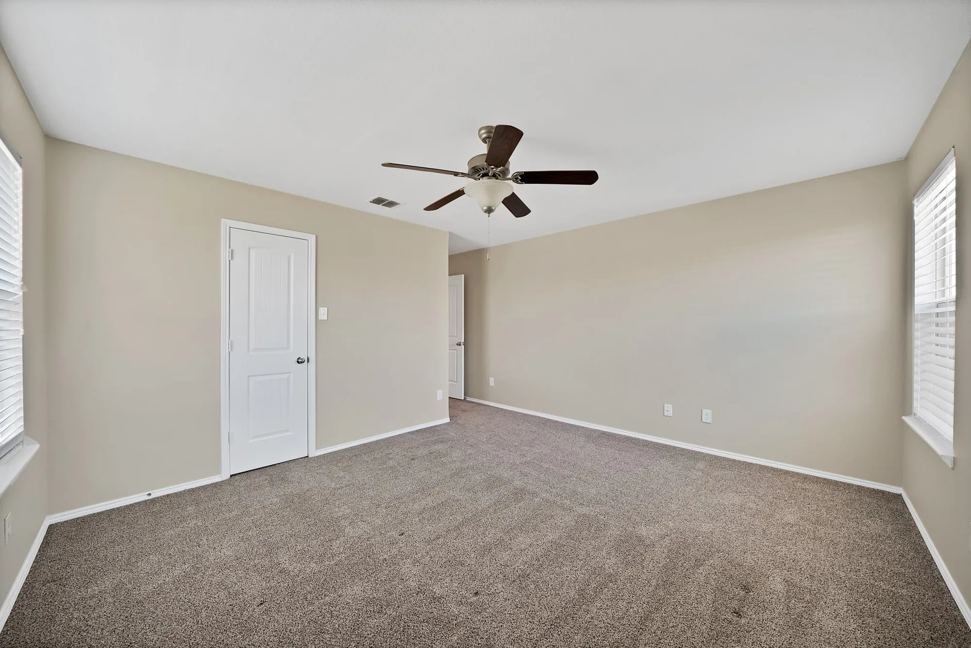 Carpeted spare room featuring ceiling fan and baseboards