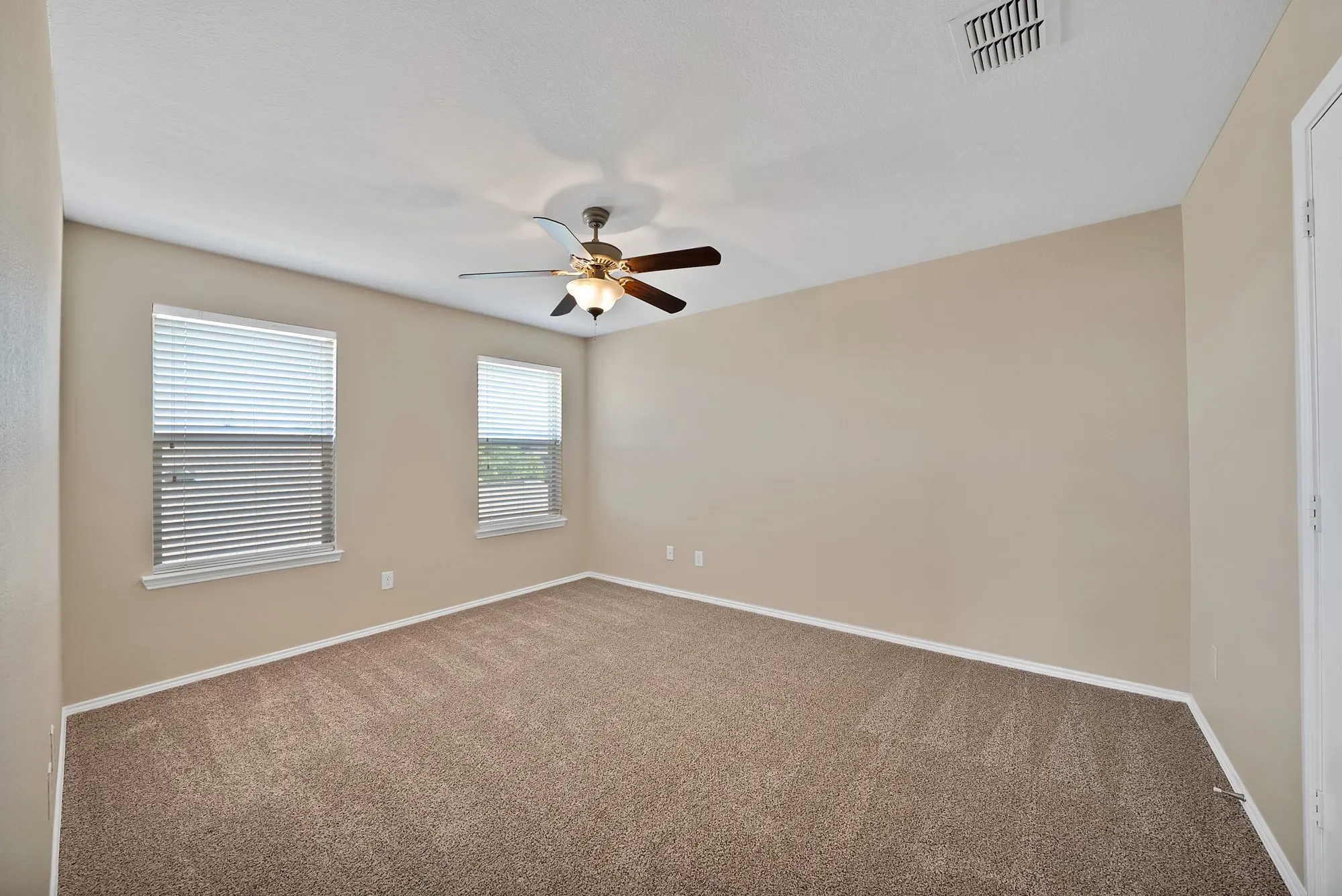 Spare room featuring a ceiling fan and dark colored carpet