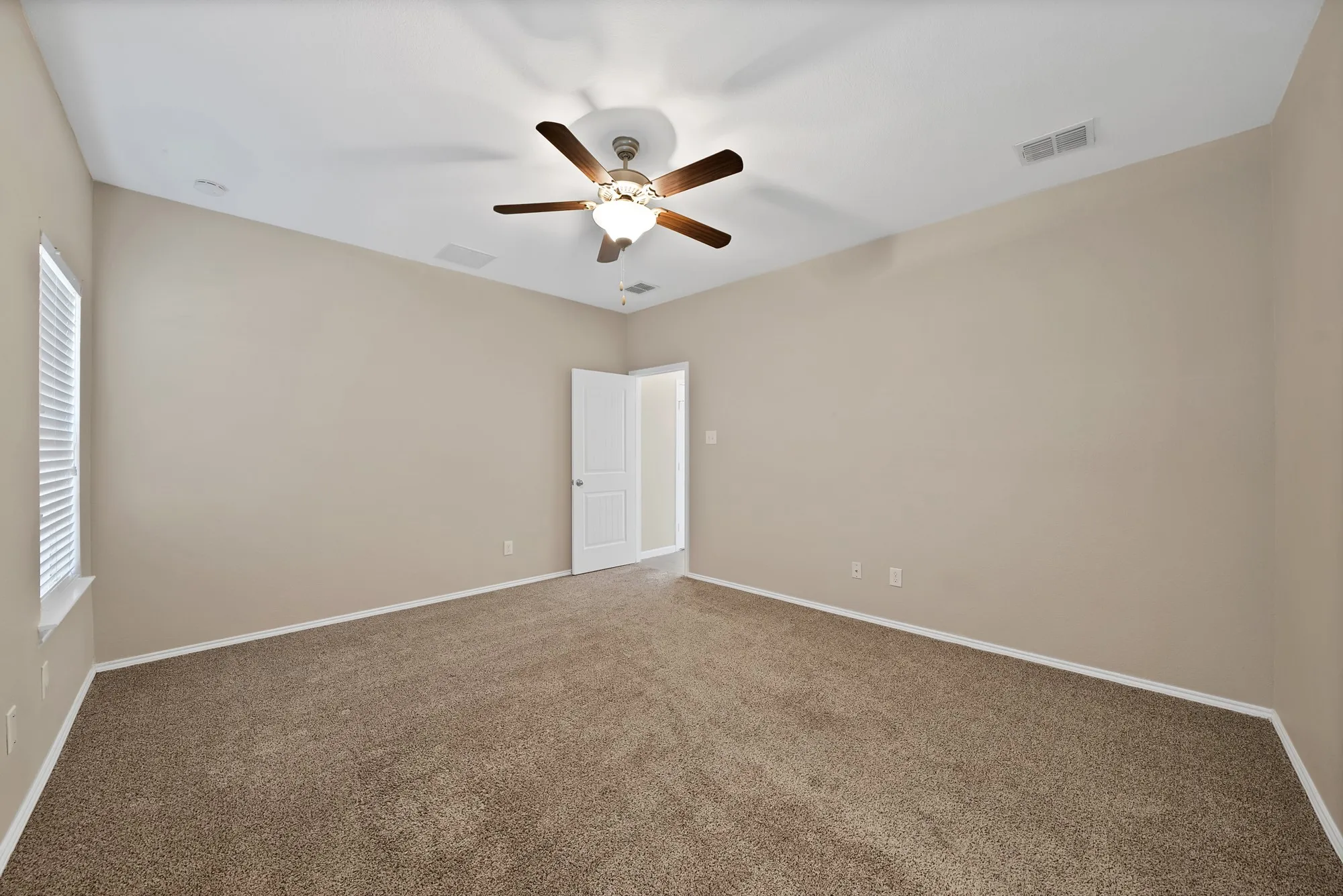 Empty room featuring dark colored carpet and a ceiling fan
