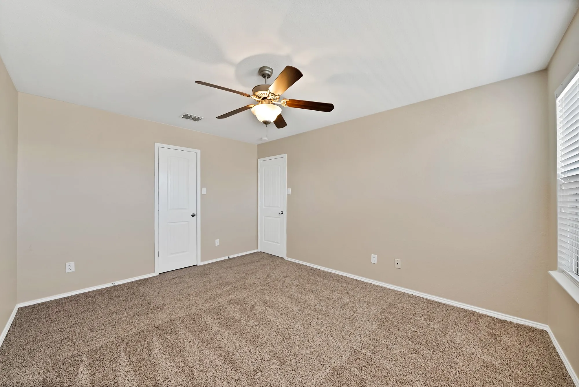 Unfurnished bedroom featuring ceiling fan, carpet floors, and multiple windows
