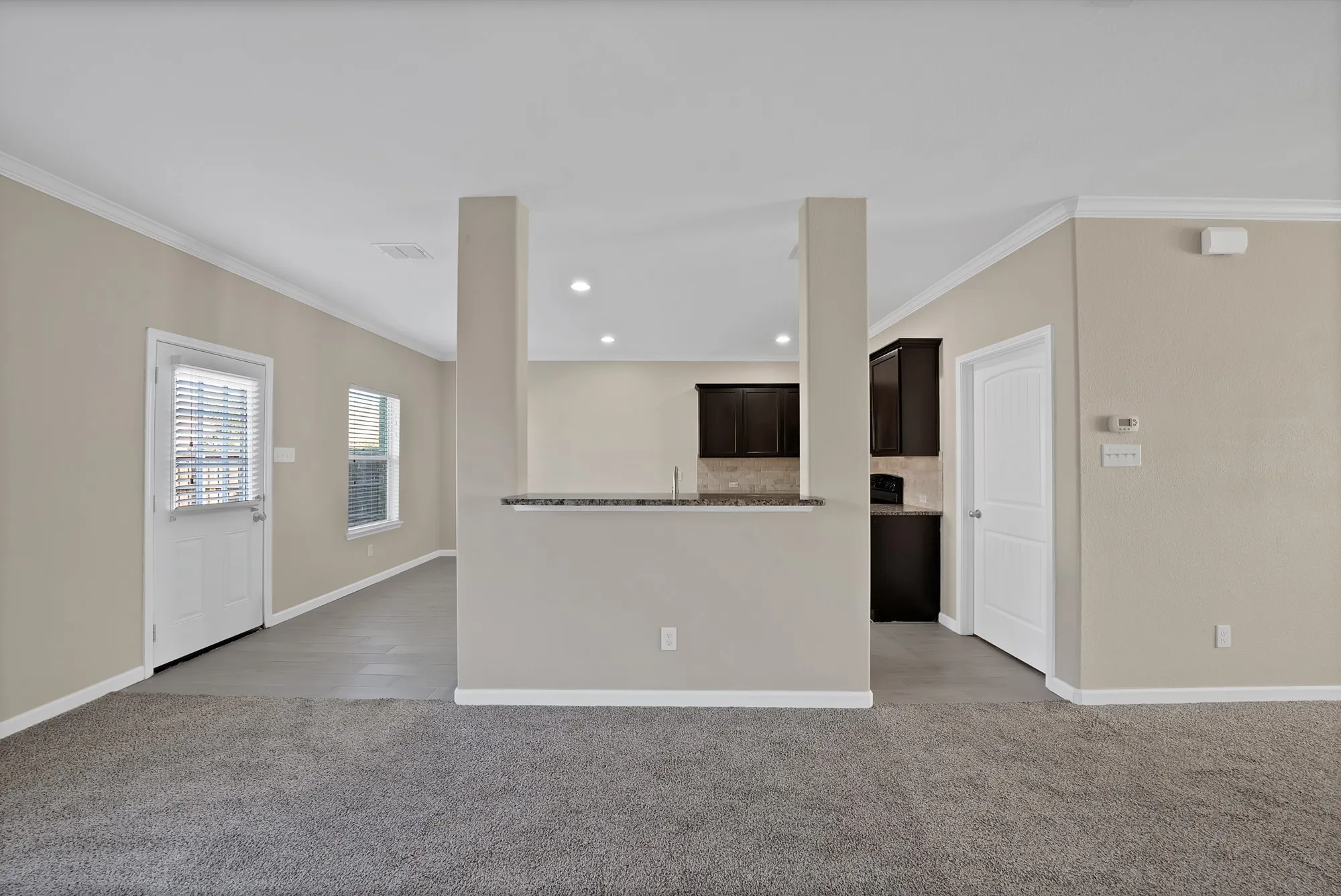 Unfurnished living room with light carpet, ornamental molding, and recessed lighting