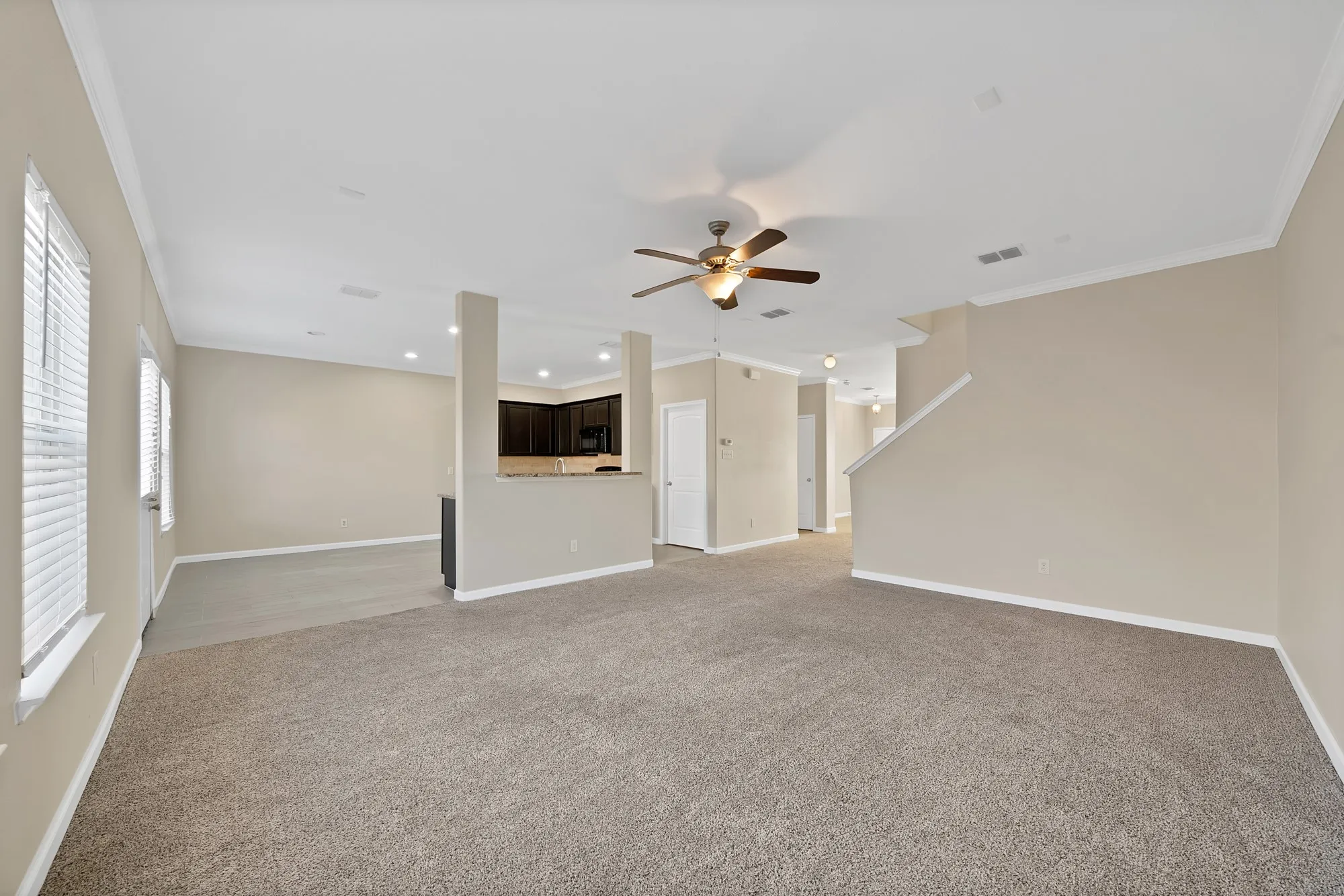Unfurnished living room featuring ornamental molding, ceiling fan, light colored carpet, and recessed lighting