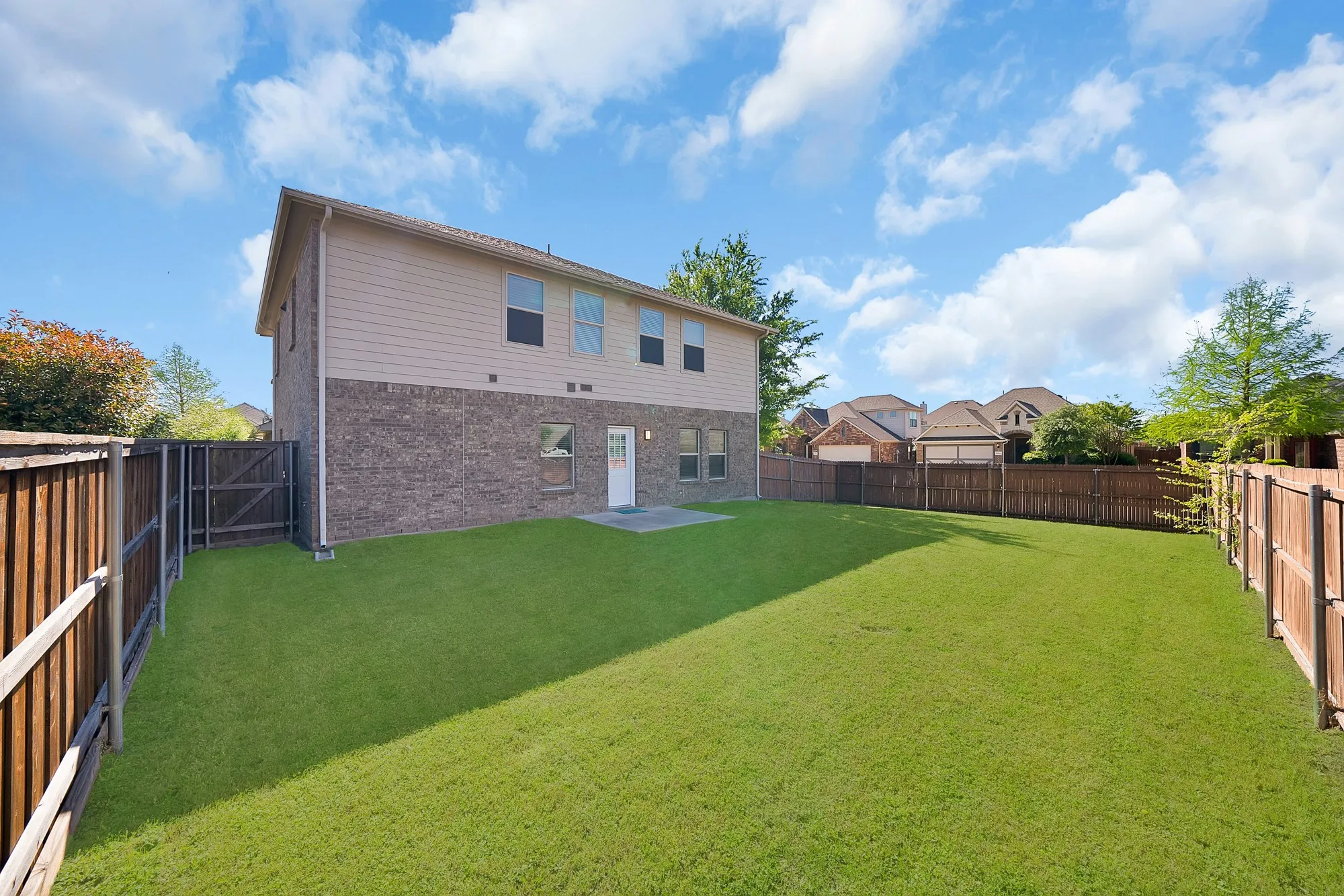 Rear view of property featuring a fenced backyard, brick siding, a patio, and a residential view