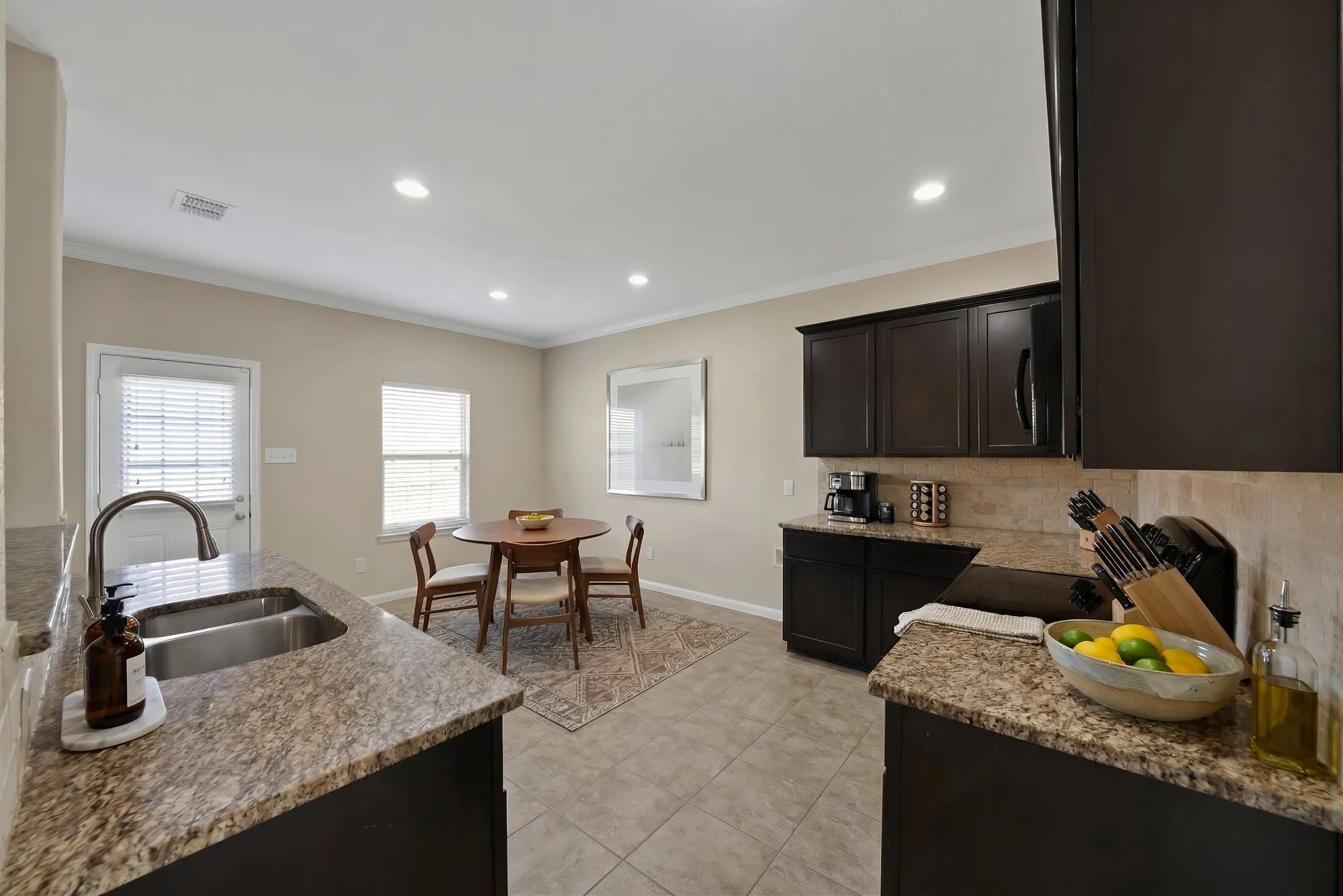 Kitchen with light stone counters, electric stove, tasteful backsplash, ornamental molding, and recessed lighting