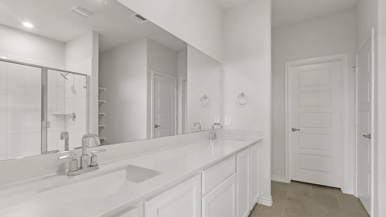 Bathroom with double vanity, a shower stall, and light tile patterned flooring