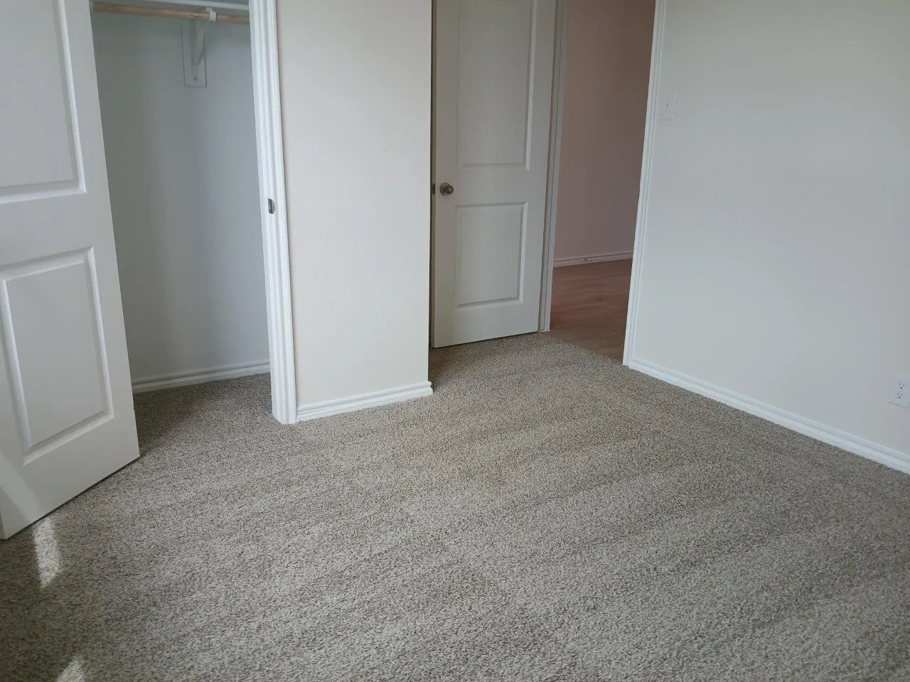 Neutral-toned carpeting extends throughout this interior space, featuring white baseboards and trim