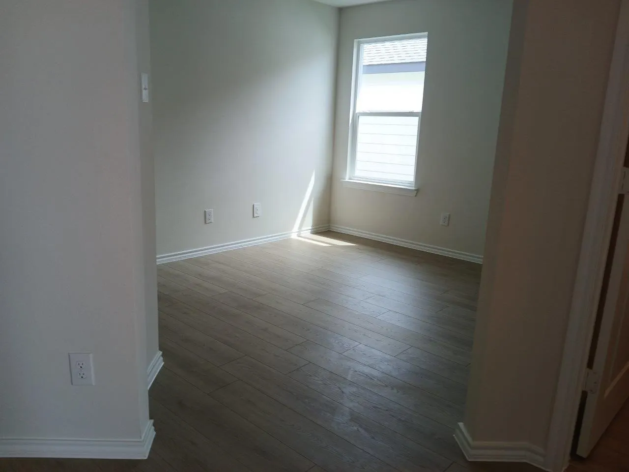 Room featuring wood-finish flooring, white baseboards, and neutral wall paint