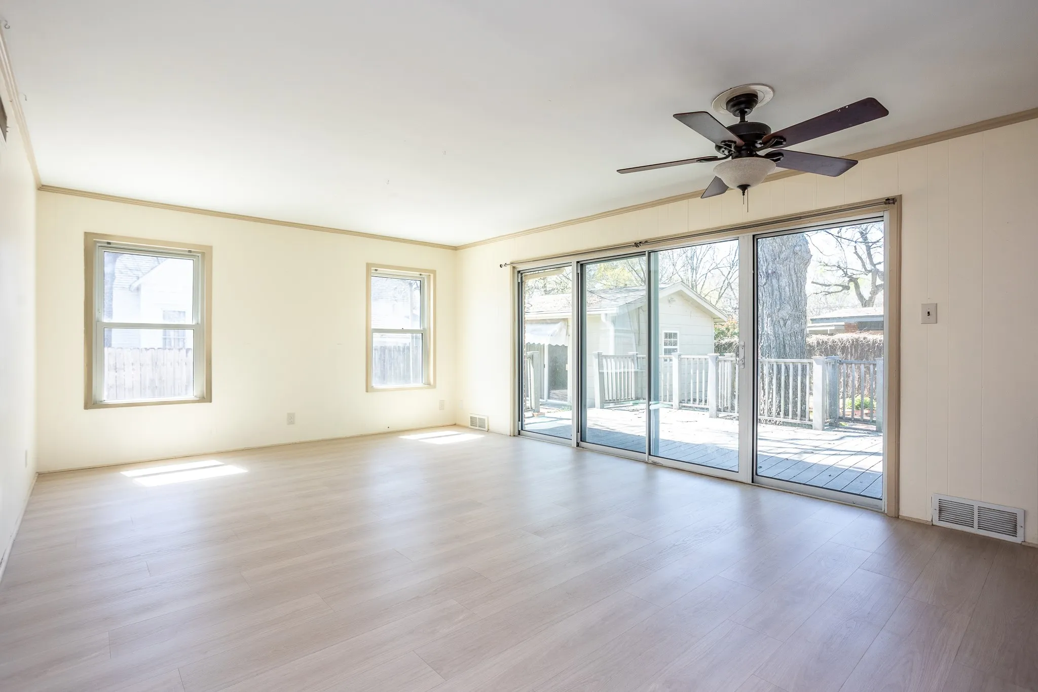 Large den has wall of doors and windows with lots of light and vinyl plank flooring.