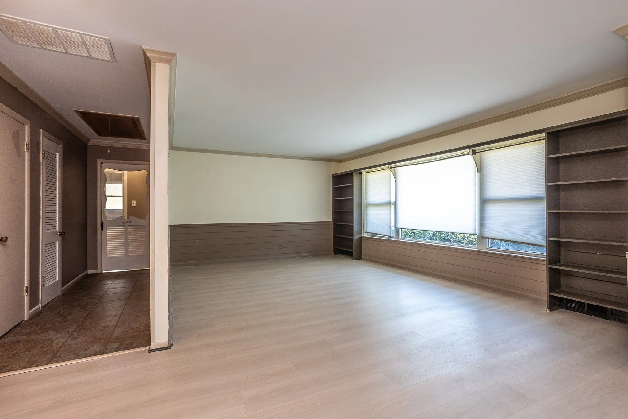 Walk into the living room with a large window and vinyl plank flooring.