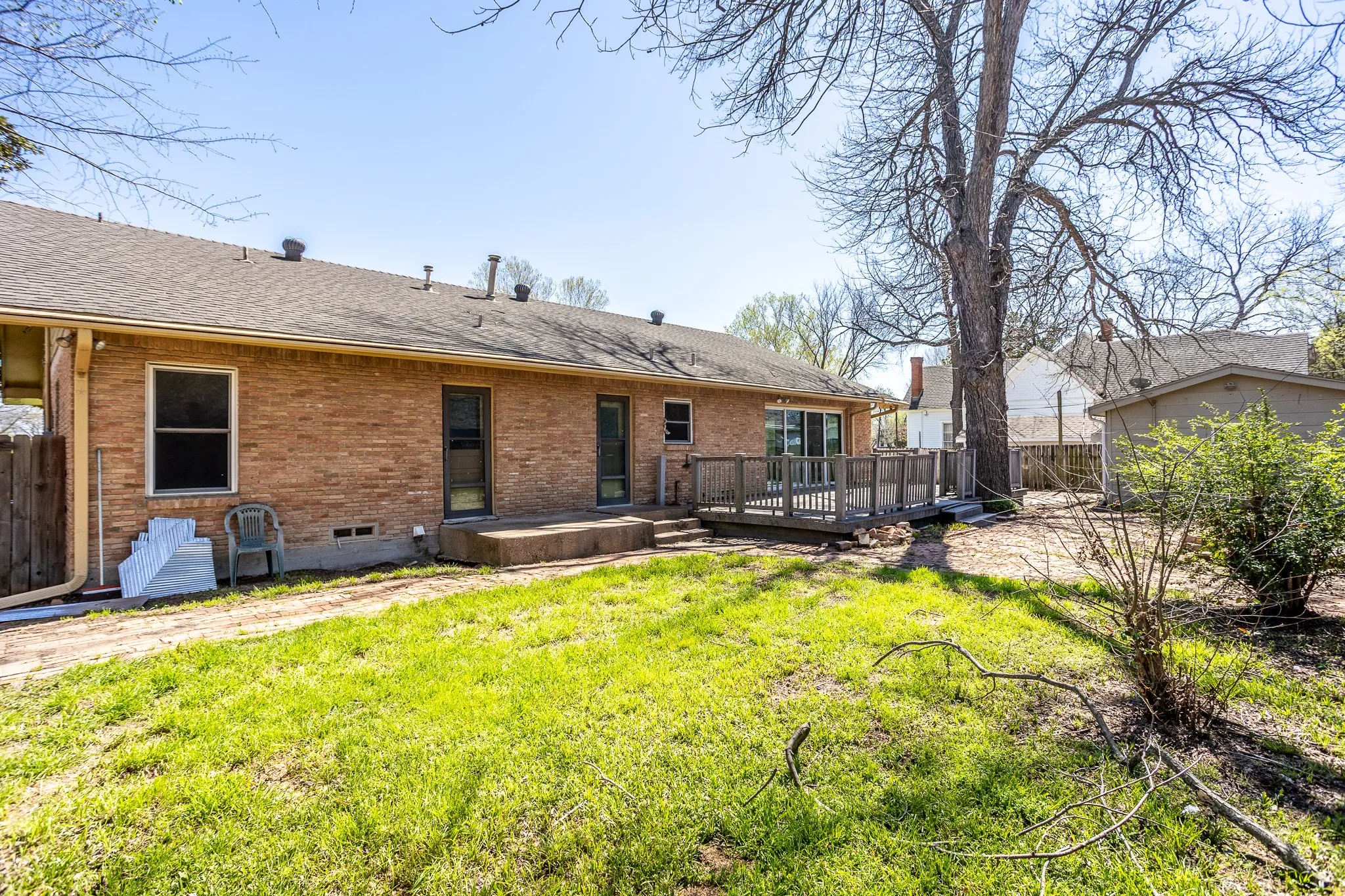 Back area of home has grass and another small storage unit.