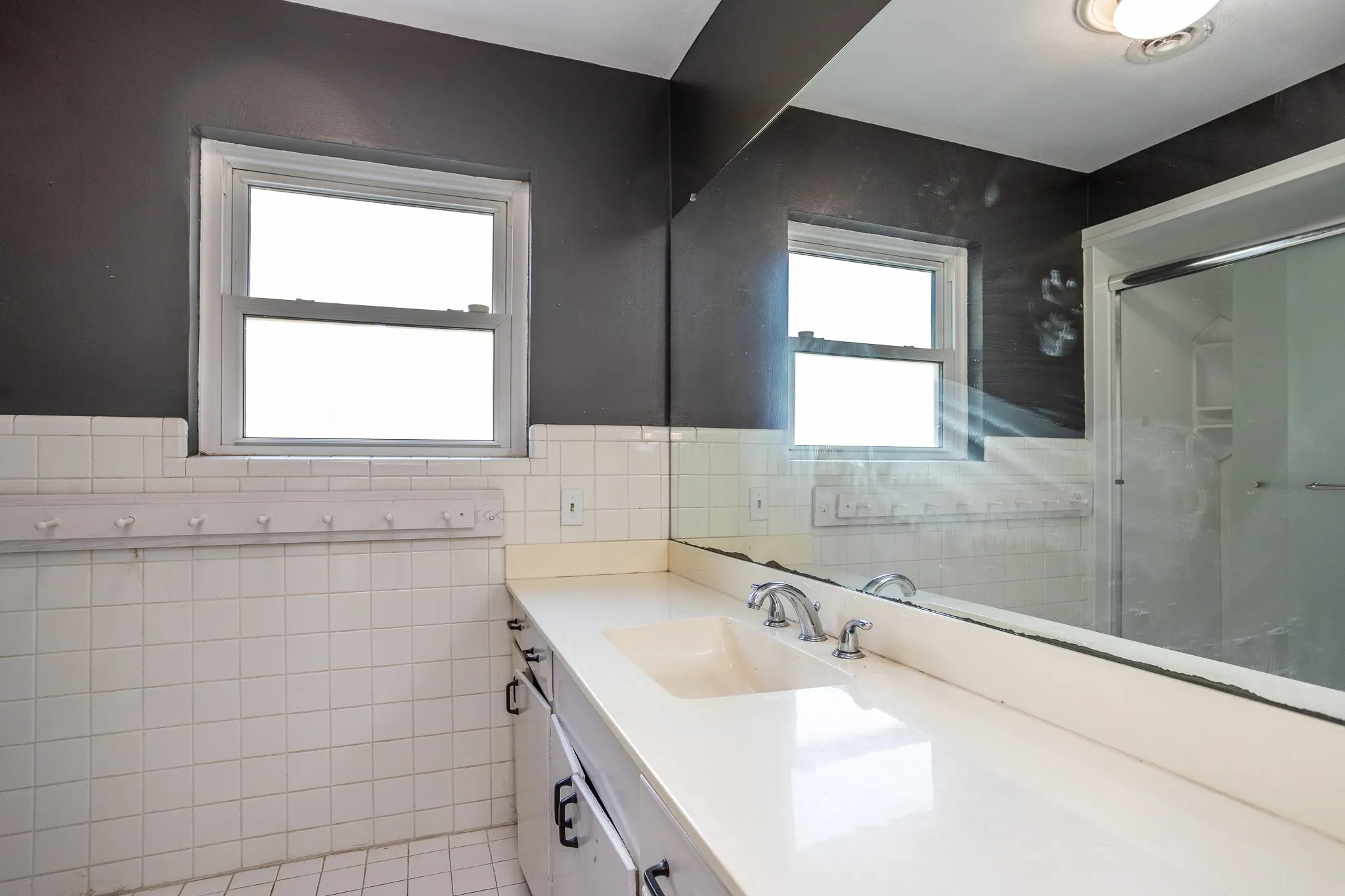 Hall sink has tile walls and man made marble counter top