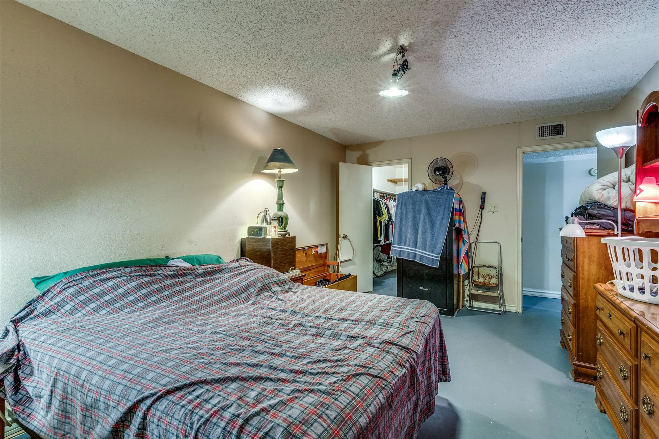 Bedroom featuring finished concrete floors, a textured ceiling, a walk in closet, and rail lighting