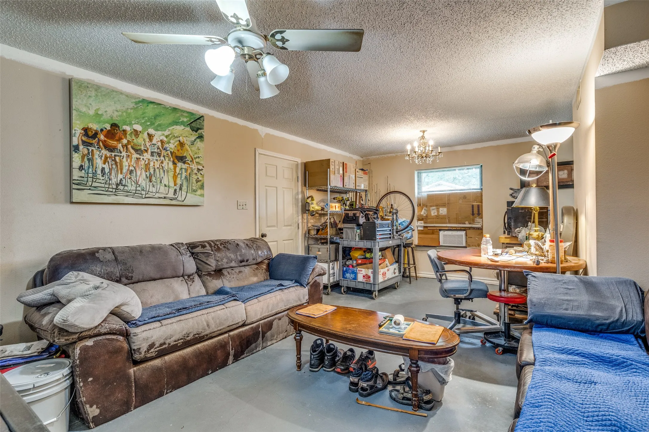 Living room with concrete floors, a textured ceiling, a chandelier, a ceiling fan, and crown molding