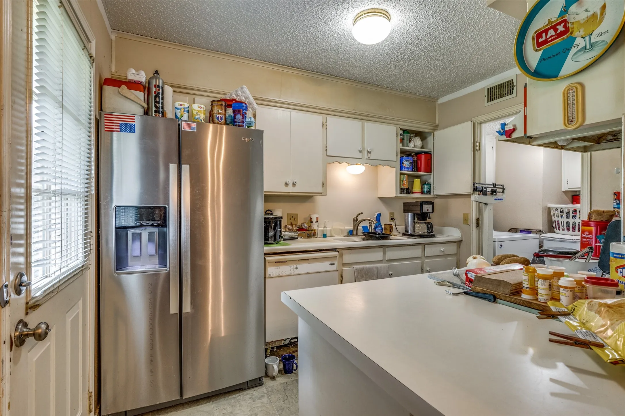 Kitchen featuring stainless steel fridge, white dishwasher, a textured ceiling, light countertops, and separate washer and dryer