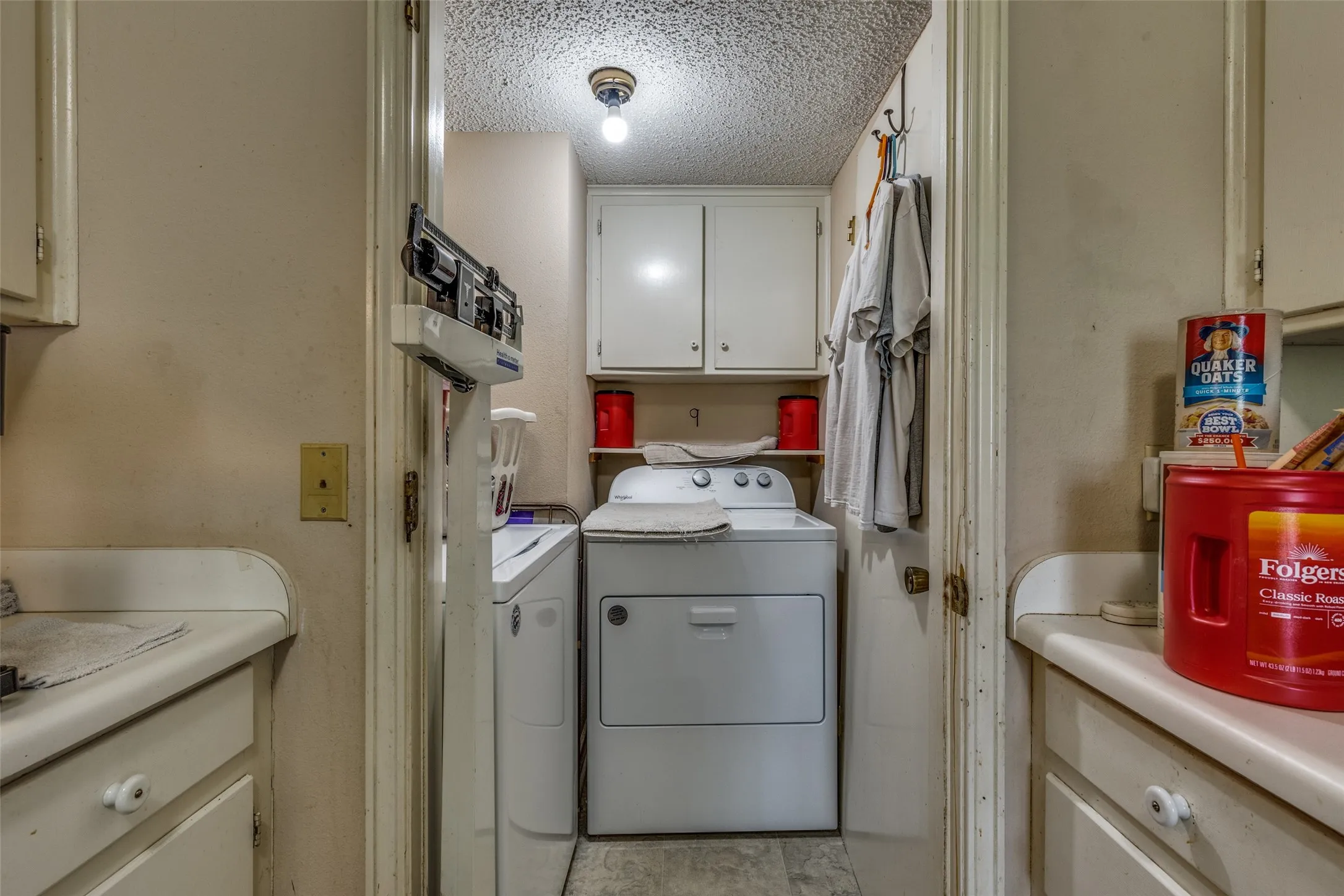 Laundry area with separate washer and dryer, cabinet space, and a textured ceiling