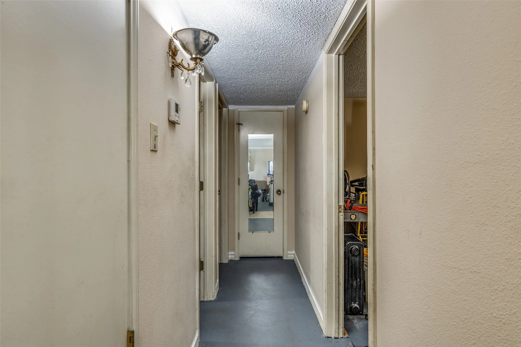 Hallway featuring finished concrete flooring, a textured ceiling, and a textured wall