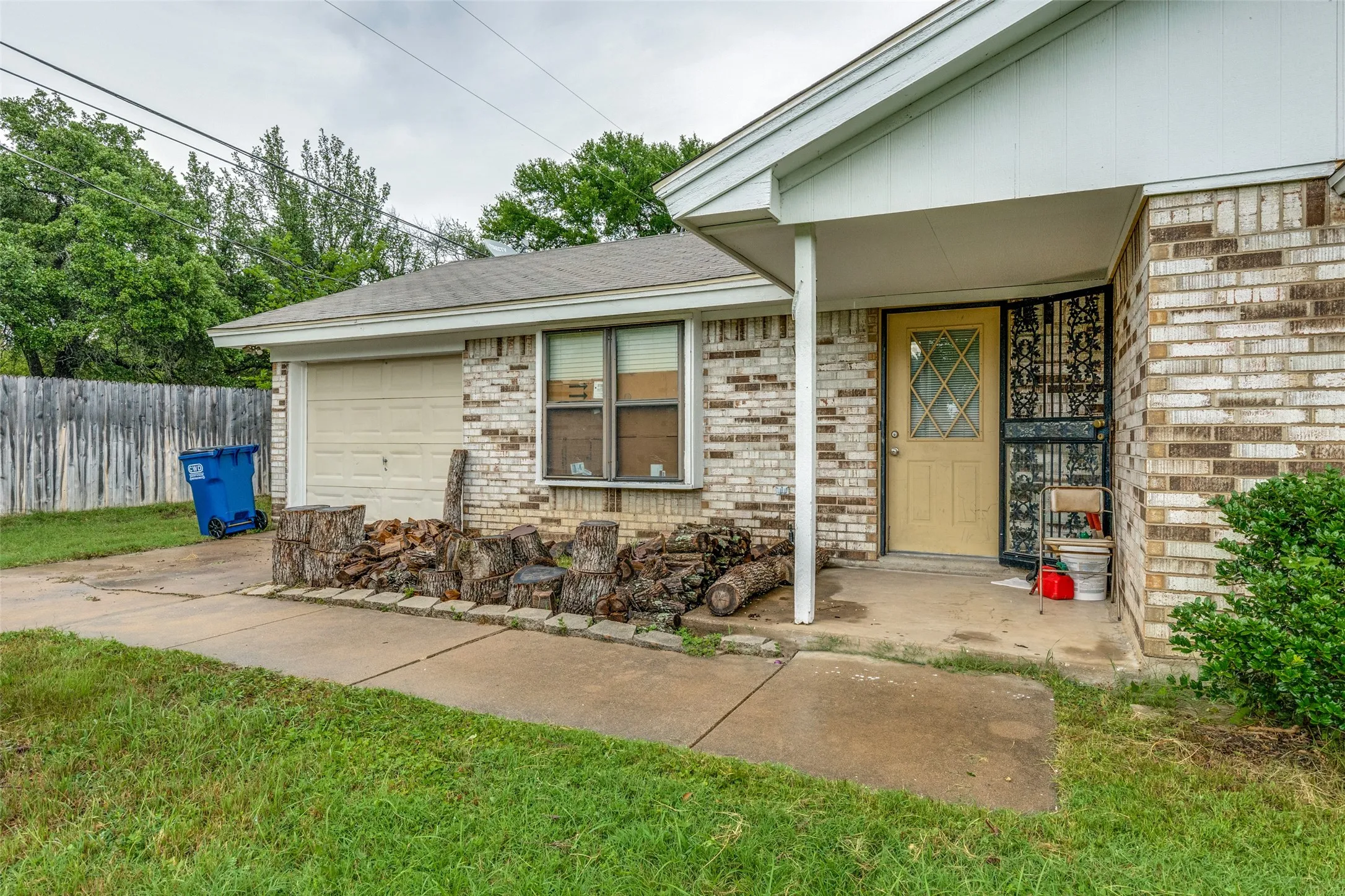Doorway to property with a garage, brick siding, and a shingled roof