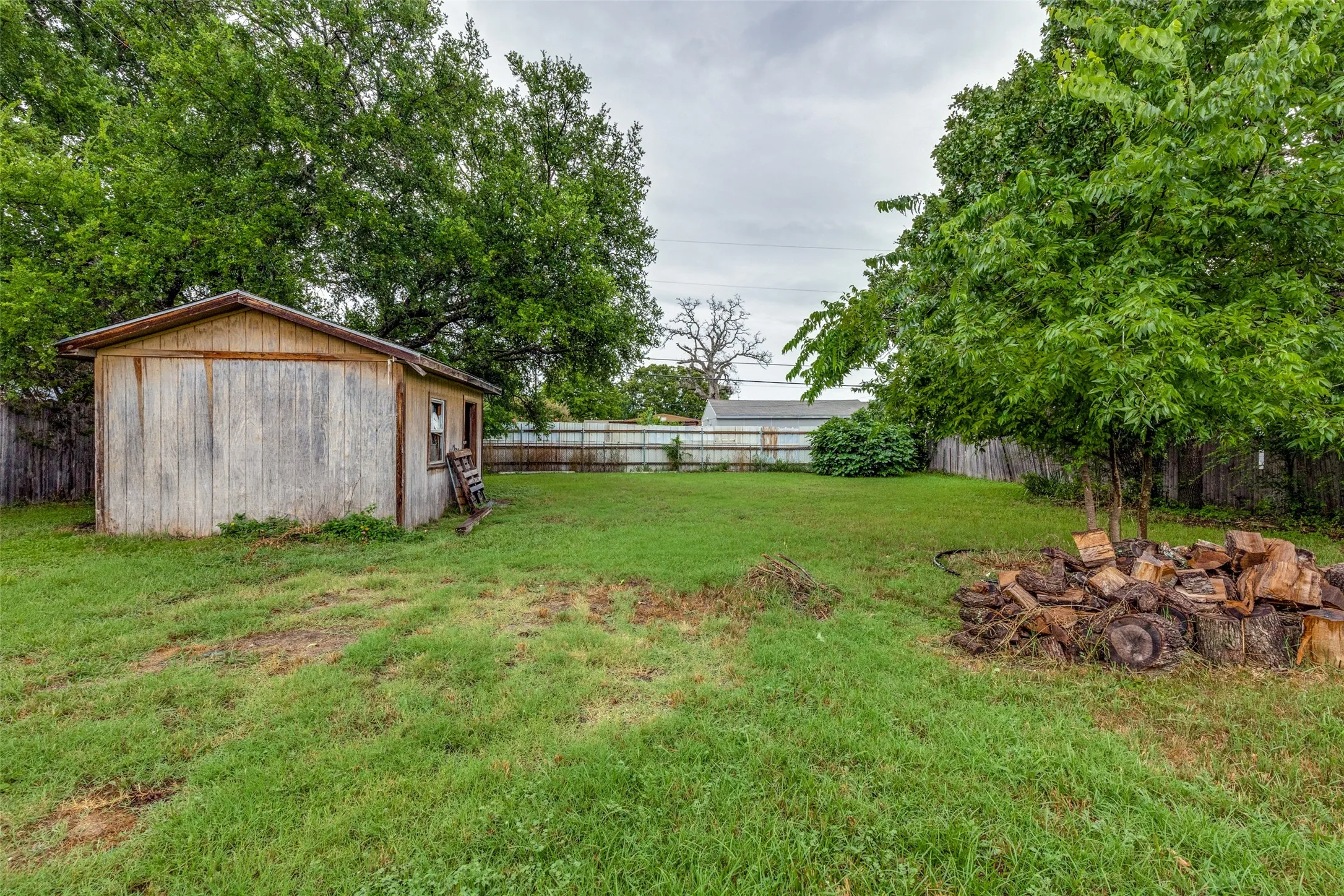 Fenced backyard featuring an outbuilding