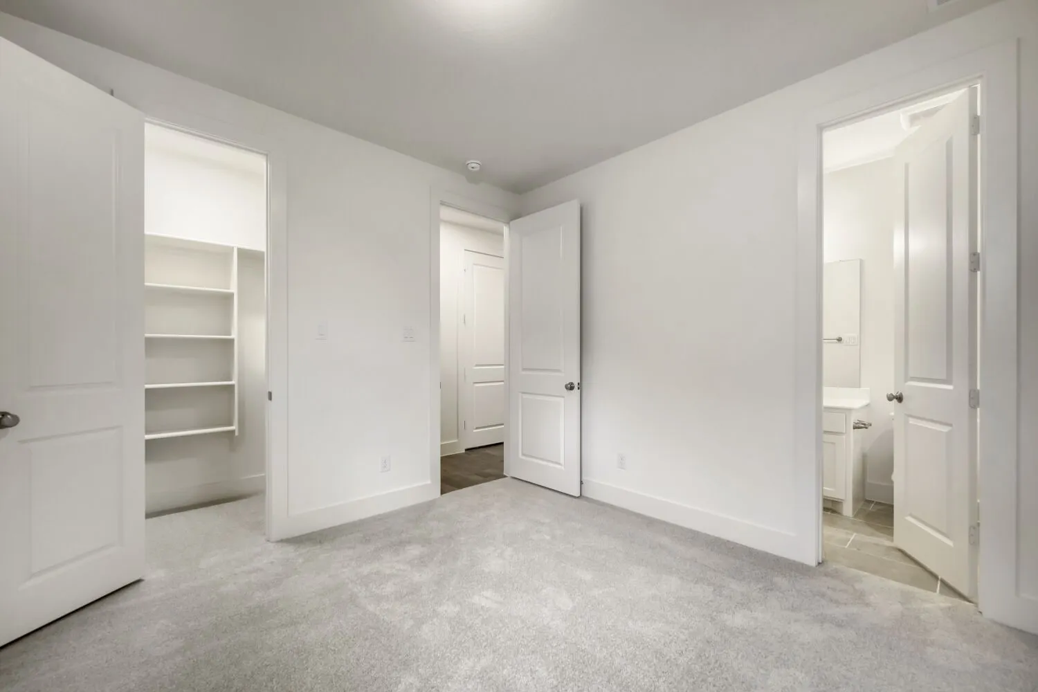 Spacious room featuring light gray carpet flooring, white walls, and bright overhead lighting