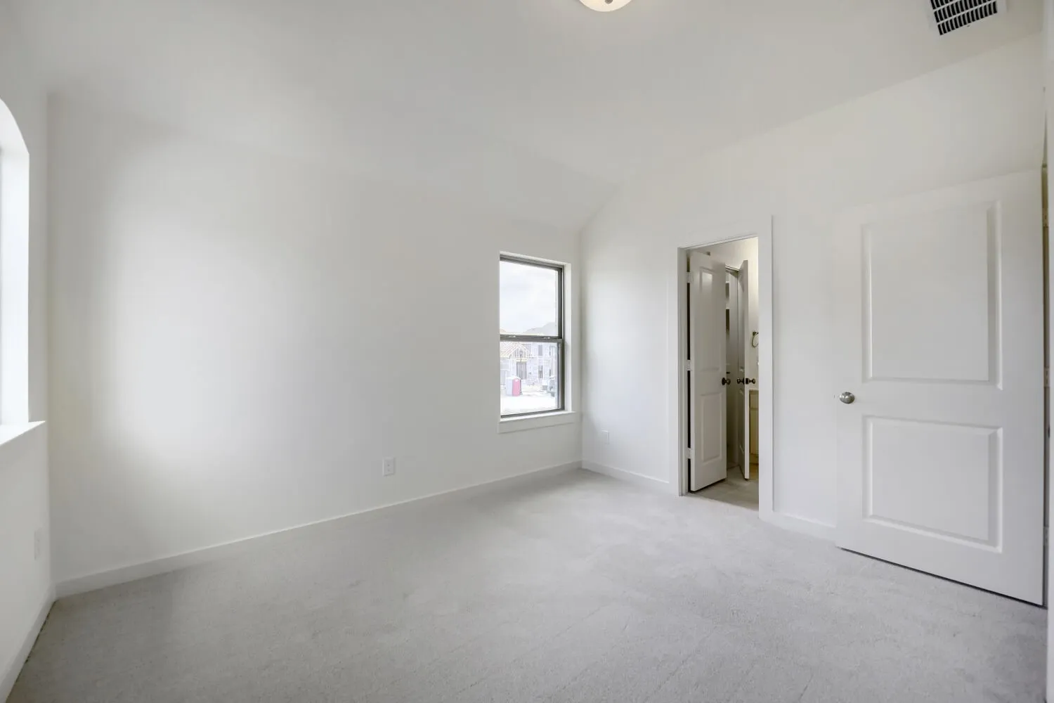 Carpeted room featuring a vaulted ceiling and two windows