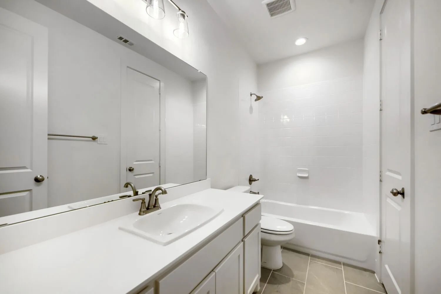 Bathroom featuring a white vanity with an integrated sink, brushed nickel faucet, and a wall-mounted mirror