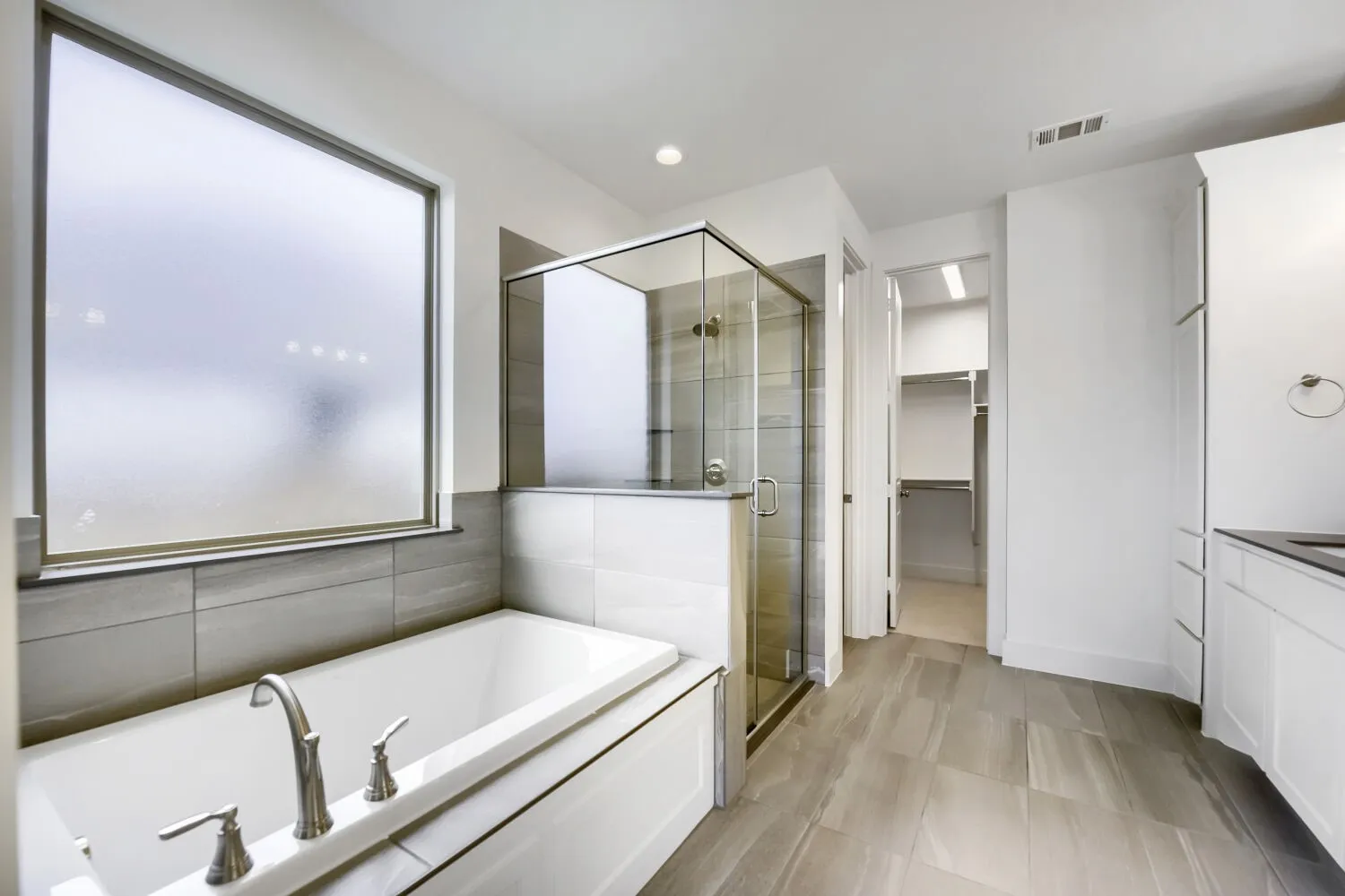 Contemporary bathroom featuring a built-in tub with brushed nickel fixtures, a glass-enclosed shower, and a large frosted window