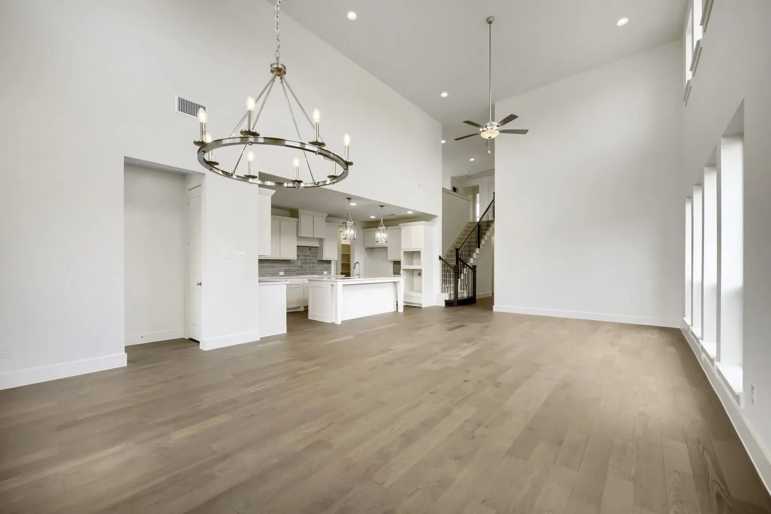 Soaring ceilings featuring a contemporary chandelier and recessed lighting