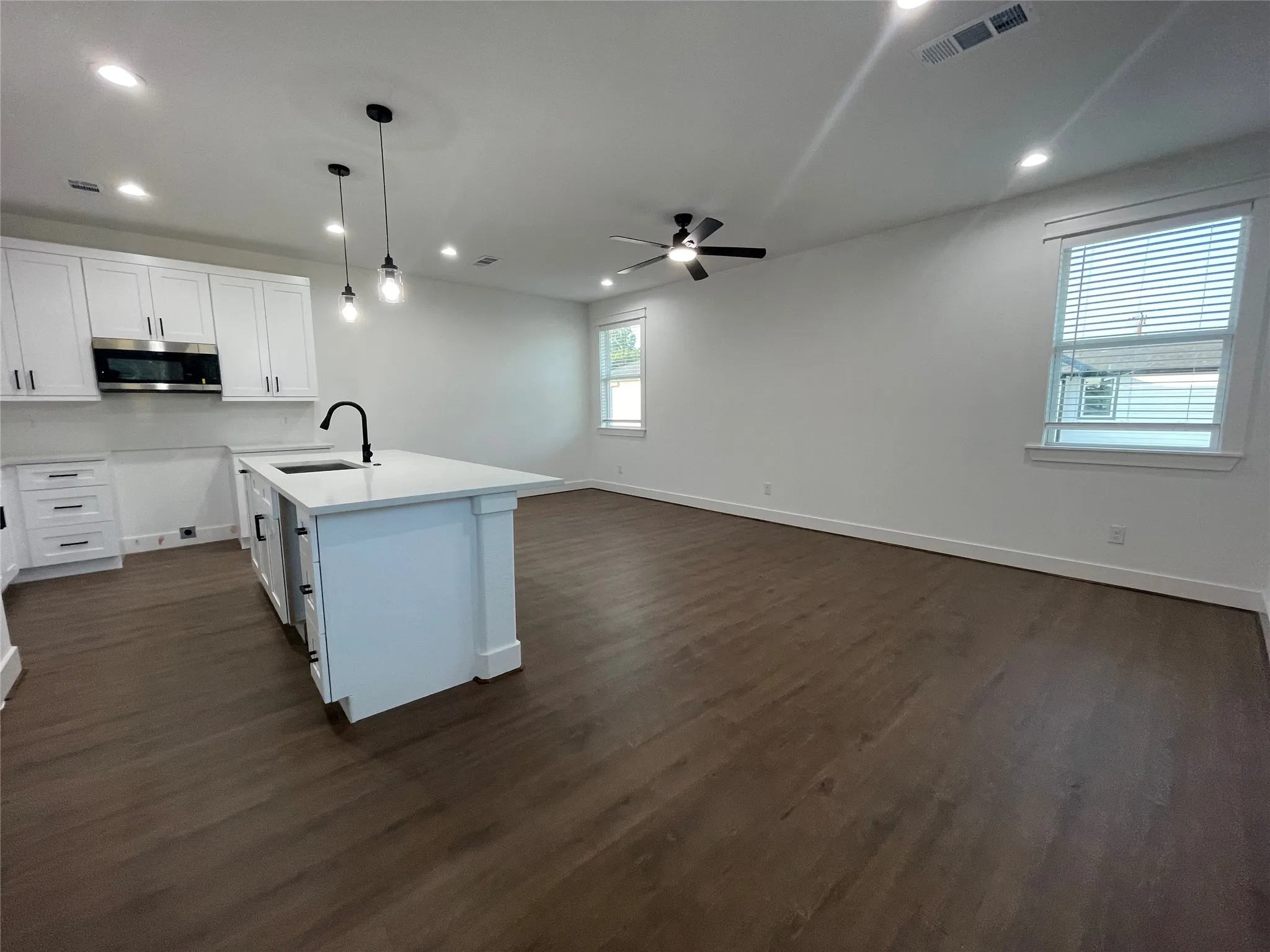 Kitchen featuring hanging light fixtures, white cabinets, open floor plan, recessed lighting, and dark wood-style flooring