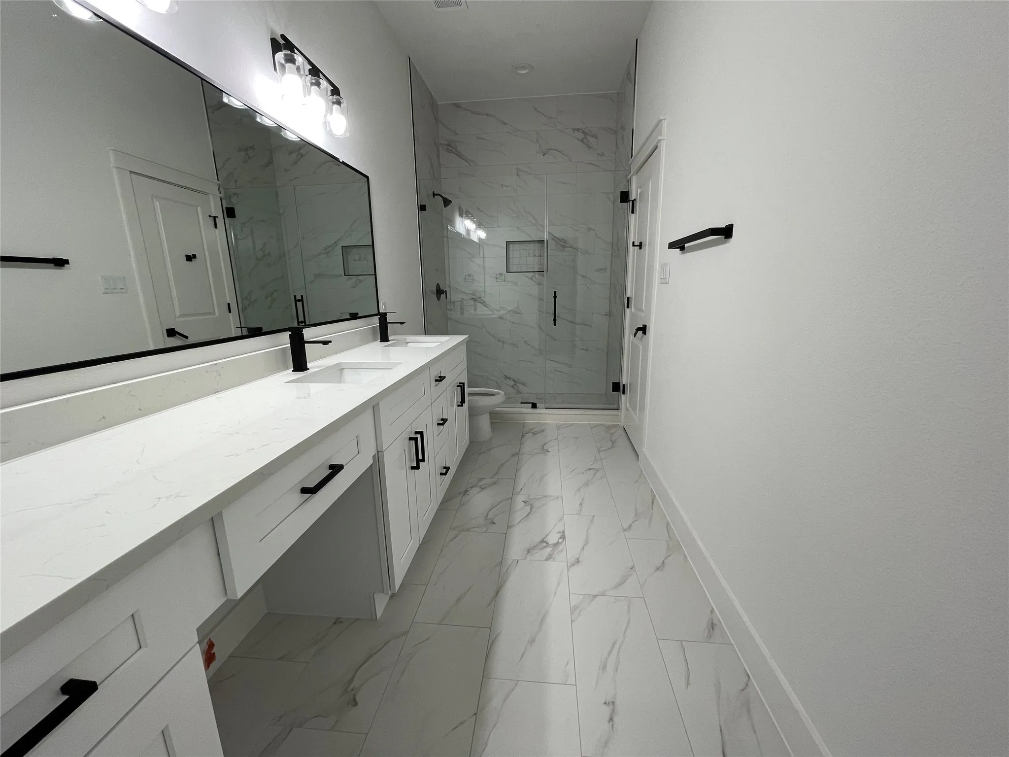 Bathroom featuring vanity, a marble finish shower, and light marble finish floors