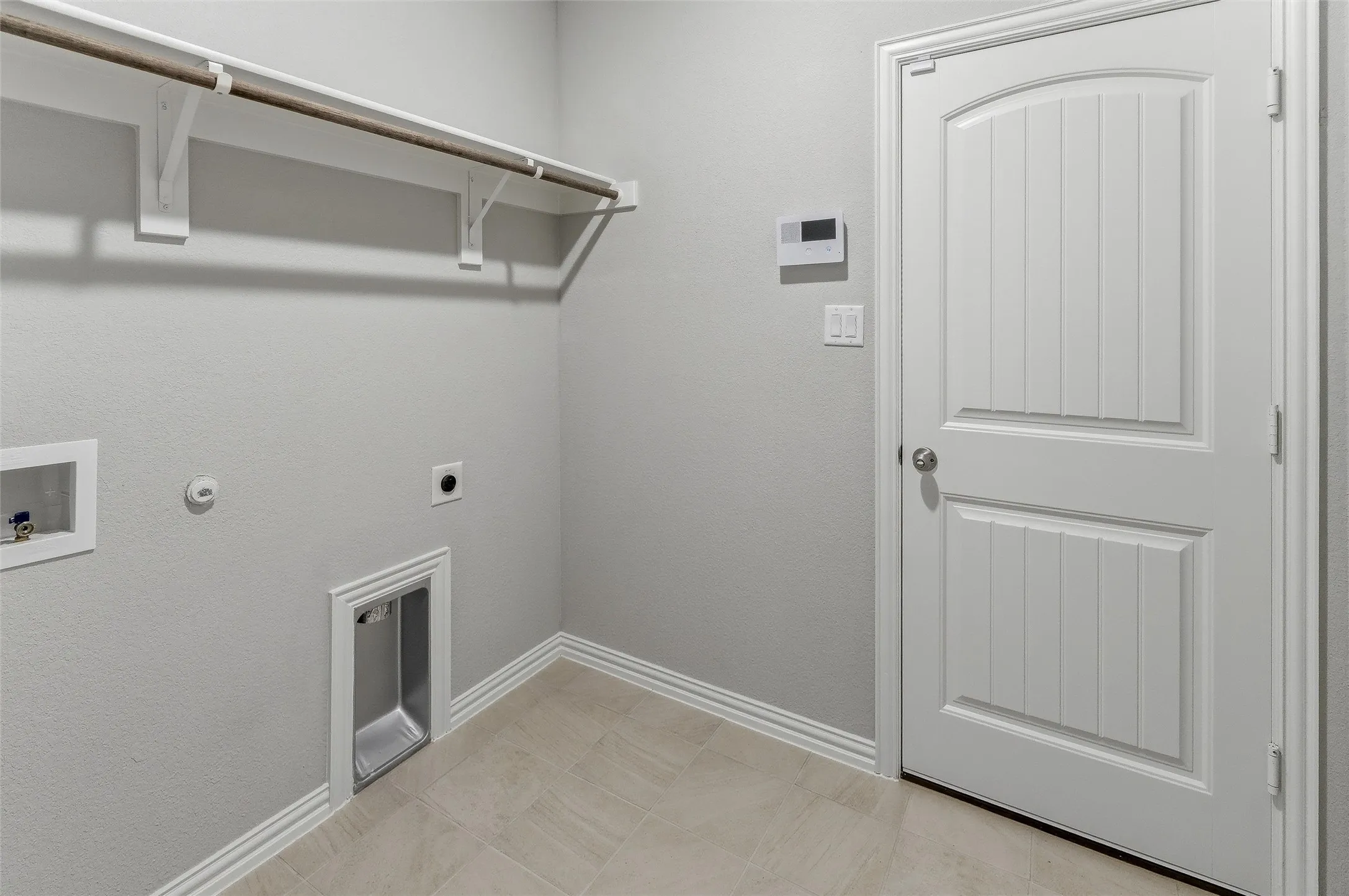 Utility area featuring light-toned tile flooring, light gray walls, and white baseboards
