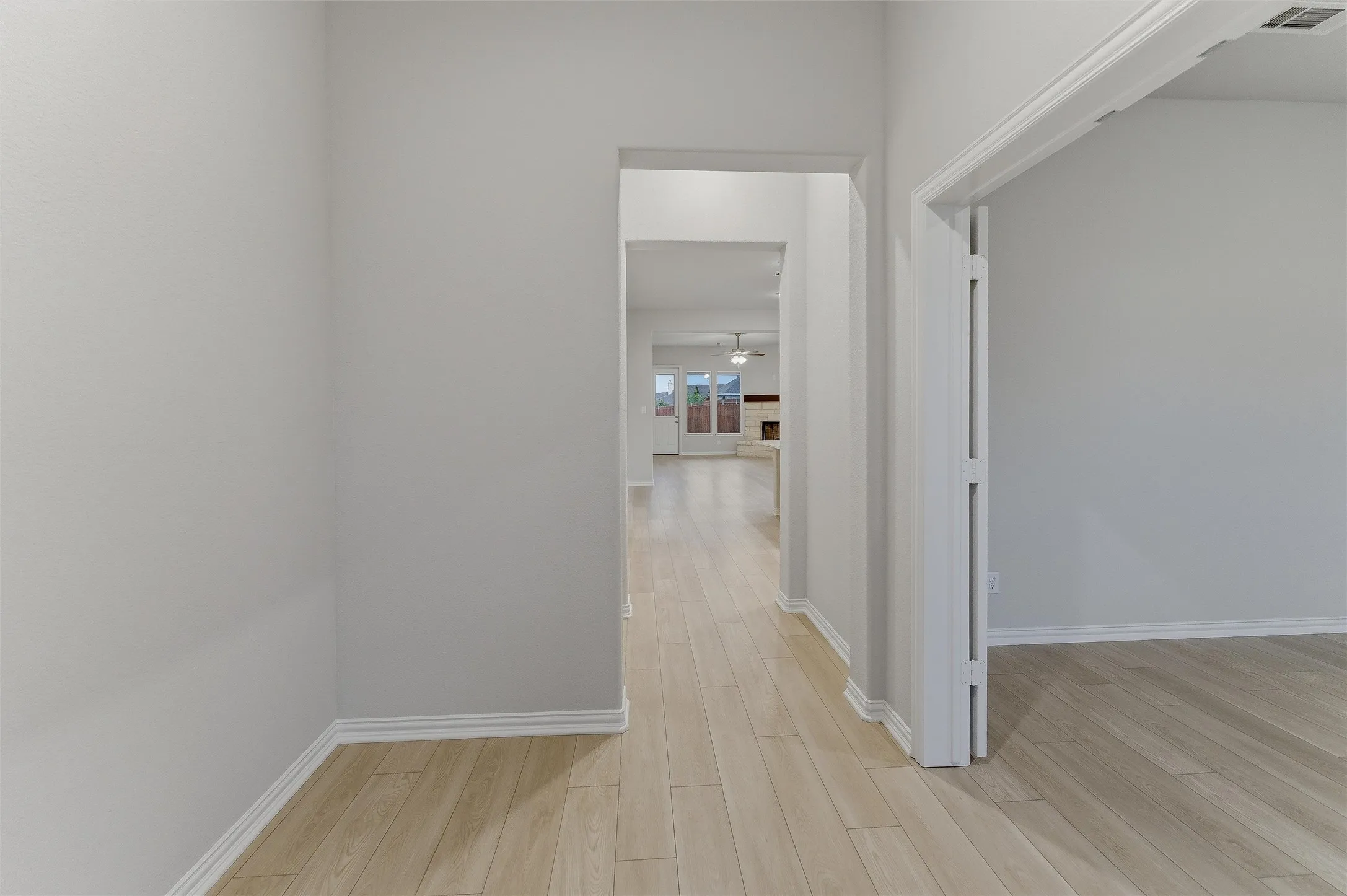 Hallway featuring wood-finish flooring, white baseboards, and light neutral wall paint