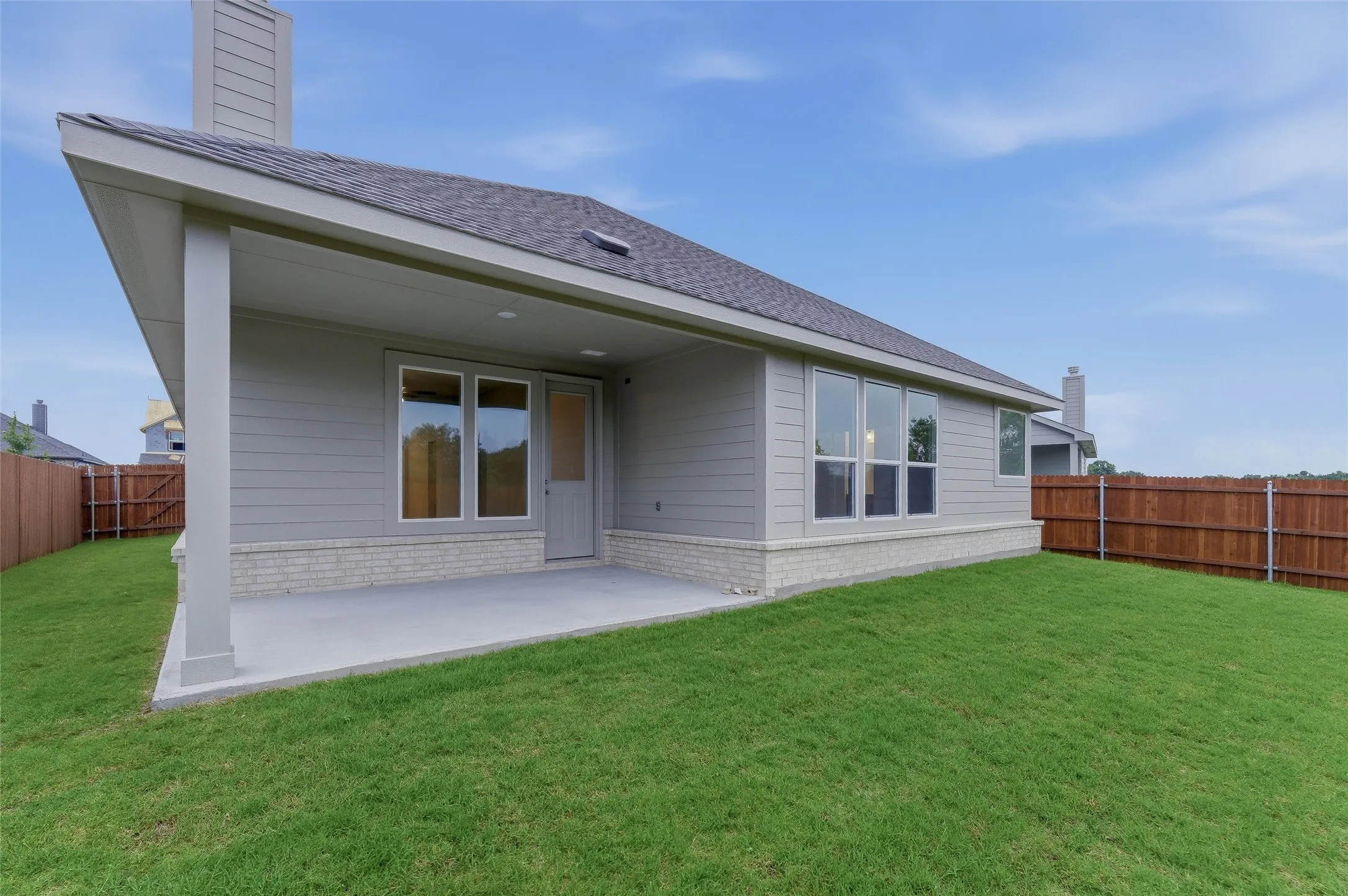 Spacious backyard featuring a covered patio, extensive lawn, and wood privacy fencing