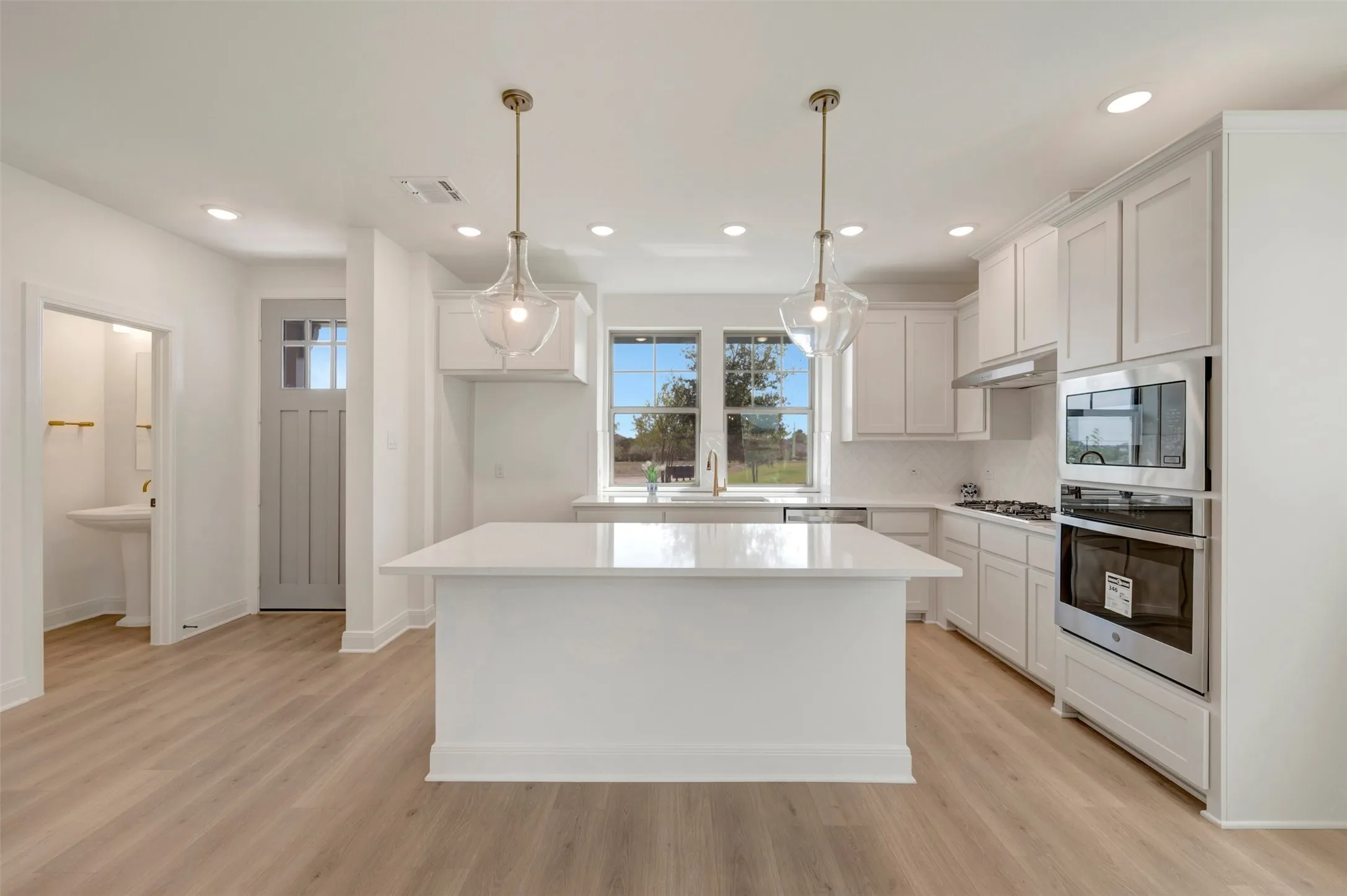 Bright kitchen featuring a central island with a solid surface countertop, white shaker-style cabinetry, and stainless steel appliances
