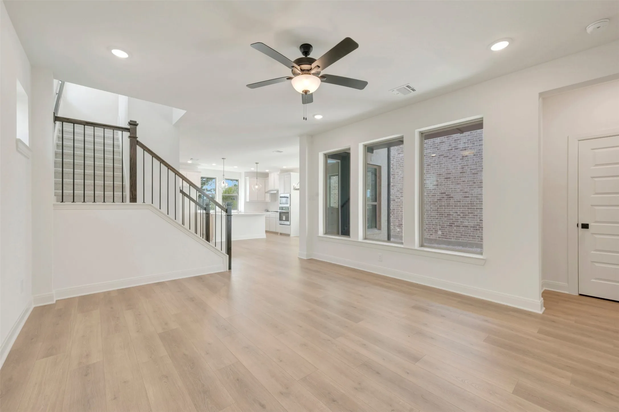 Open-concept great room featuring wood-finish flooring throughout, recessed lighting, and a ceiling fan with integrated light fixture