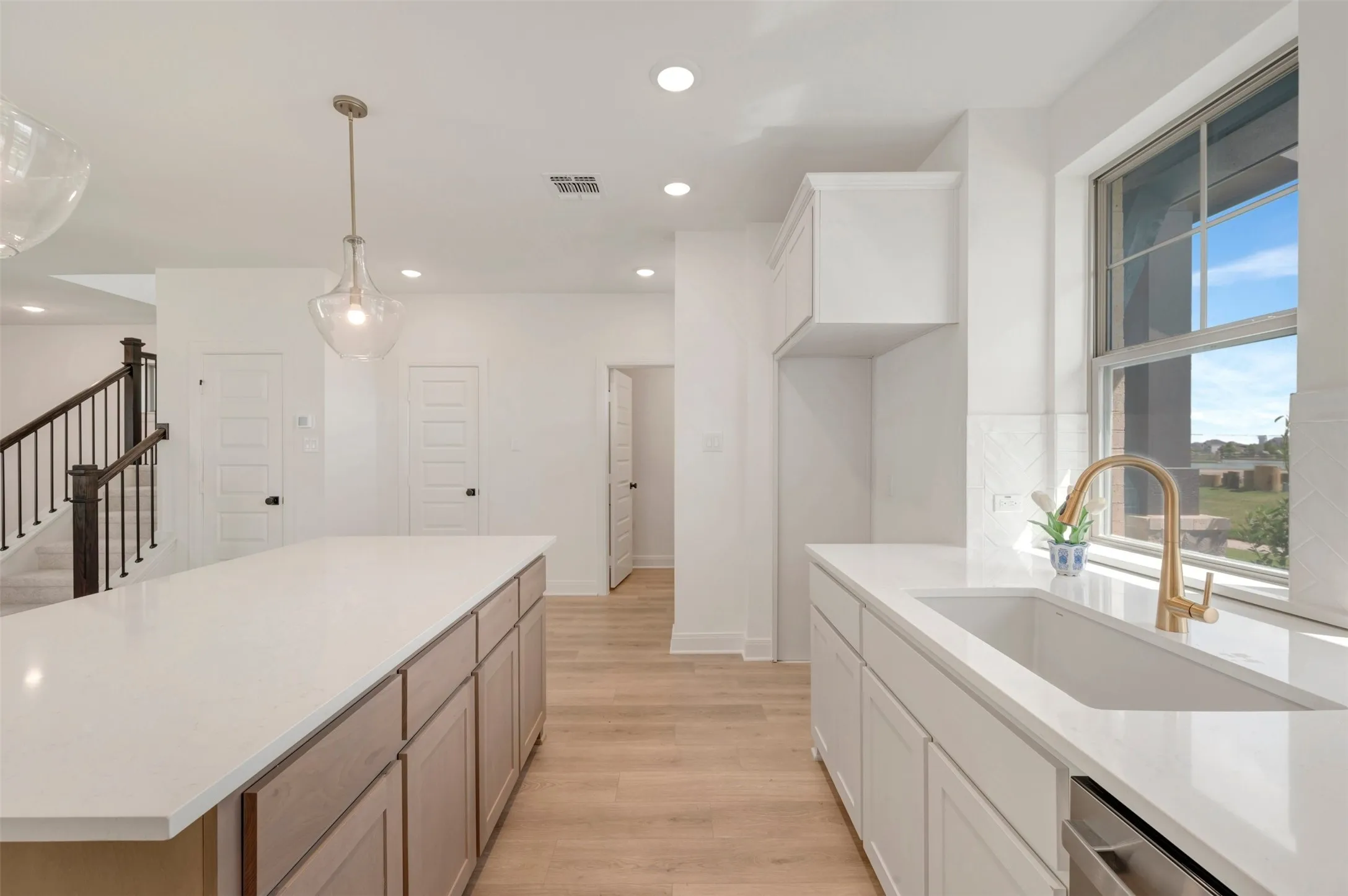 Chef's kitchen featuring a large center island with wood-finish cabinetry, white quartz countertops, and a professional stainless steel sink with brass faucet