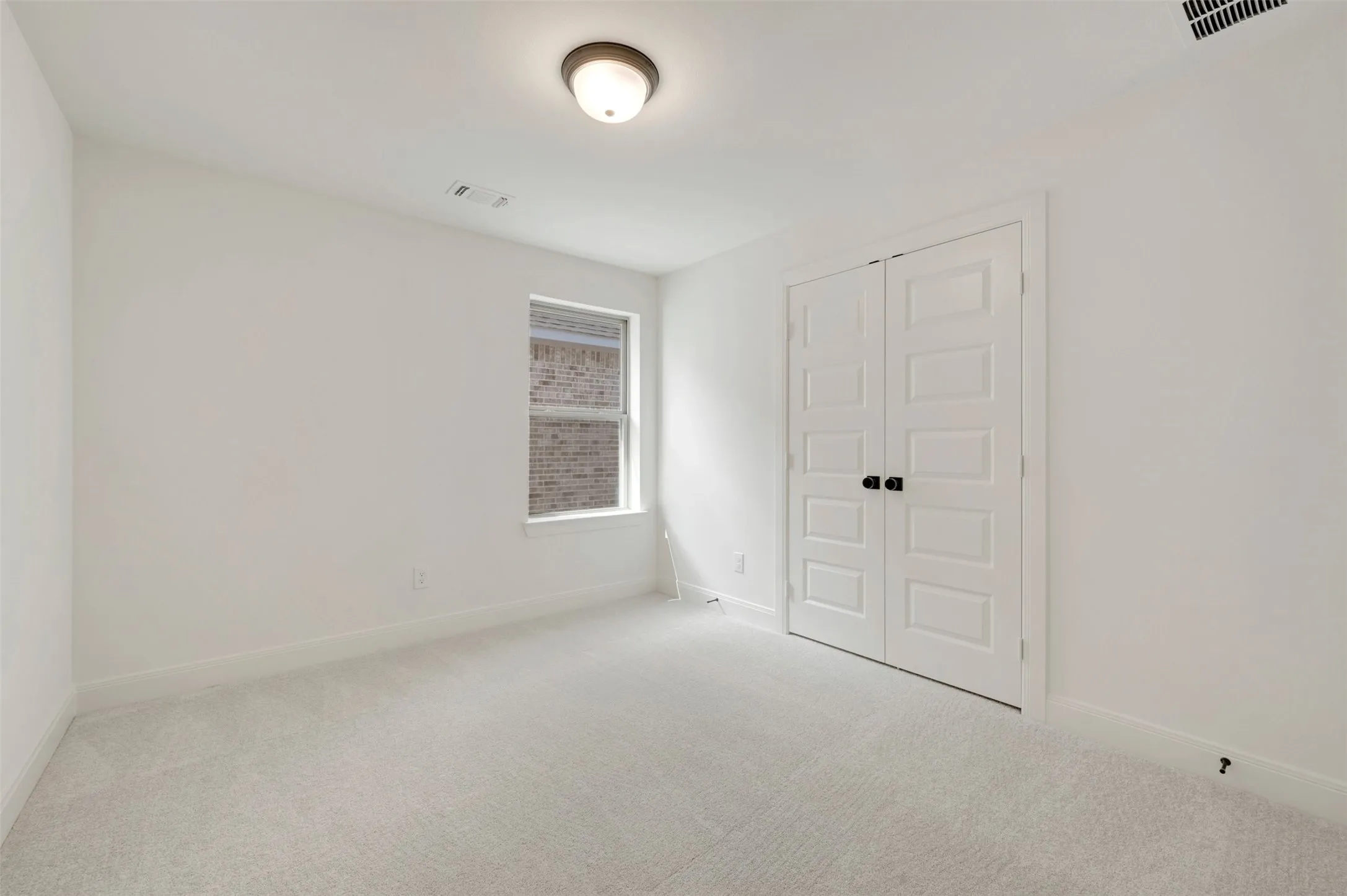 Carpeted room featuring a double-pane window, white walls, white trim, a flush mount ceiling light, and bi-fold panel doors with matte black hardware