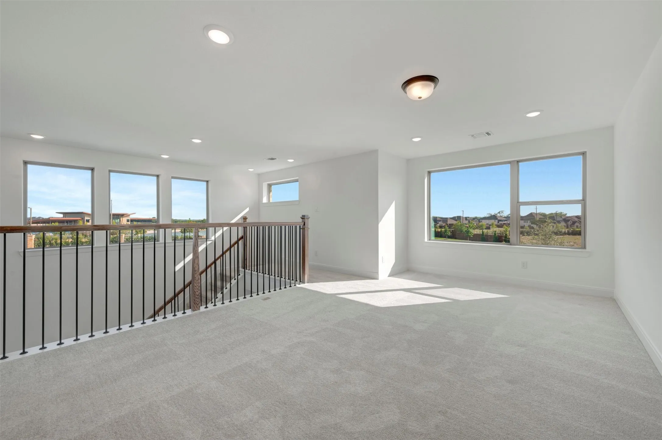 Spacious carpeted loft area with extensive natural light from multiple windows