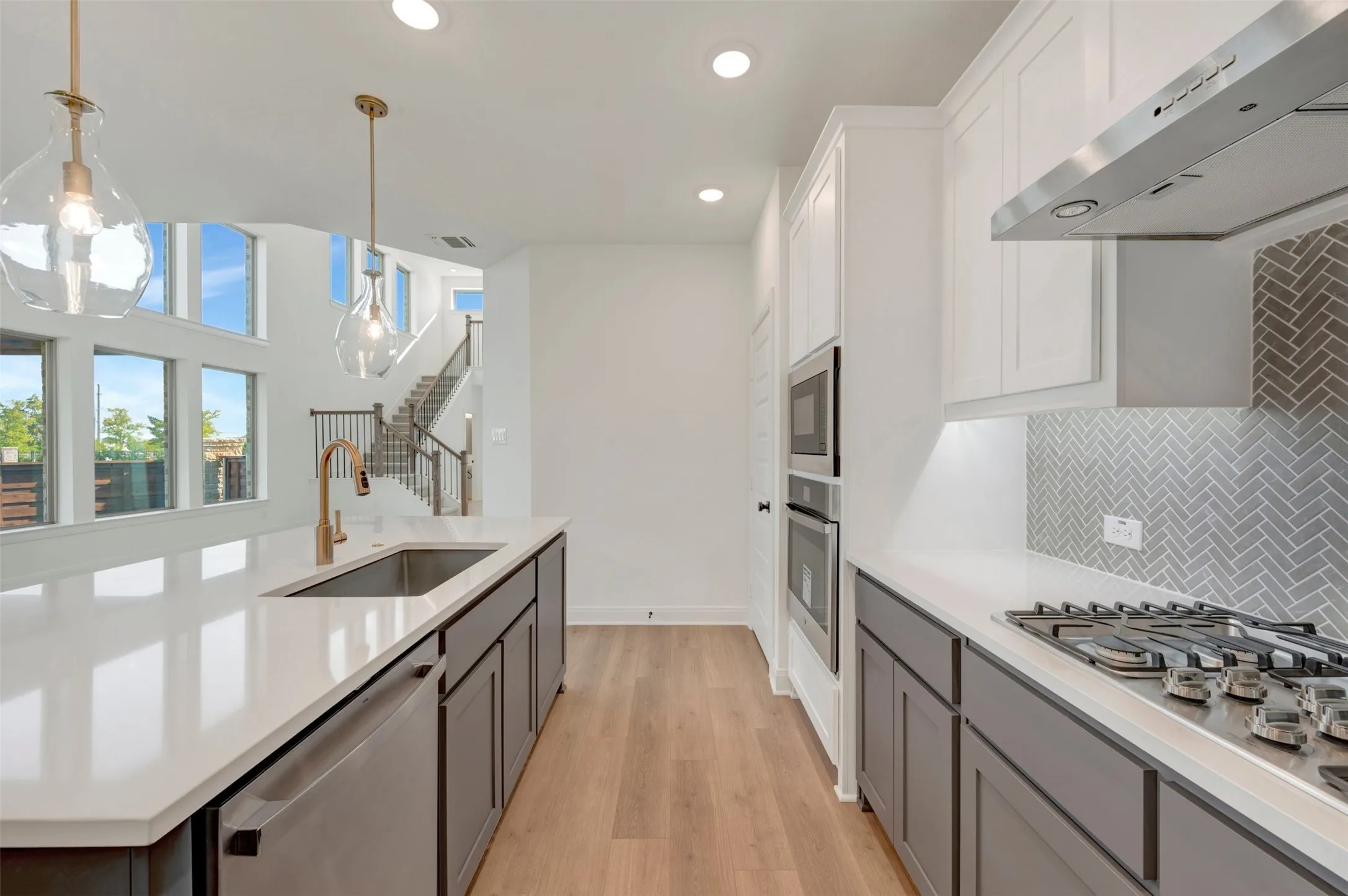 Modern kitchen featuring white countertops, a herringbone tile backsplash, and a gas cooktop