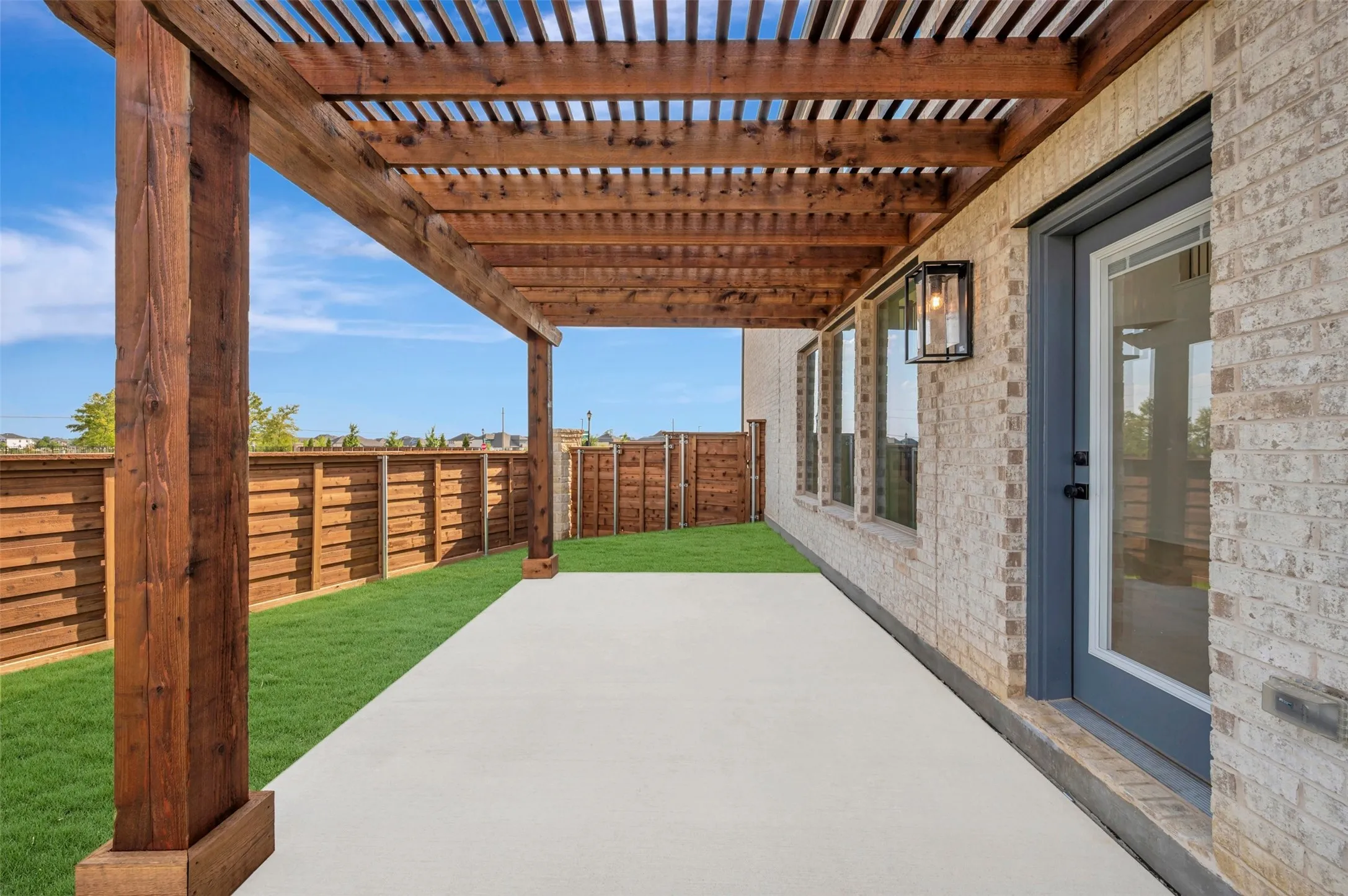 Expansive concrete patio beneath a wooden pergola