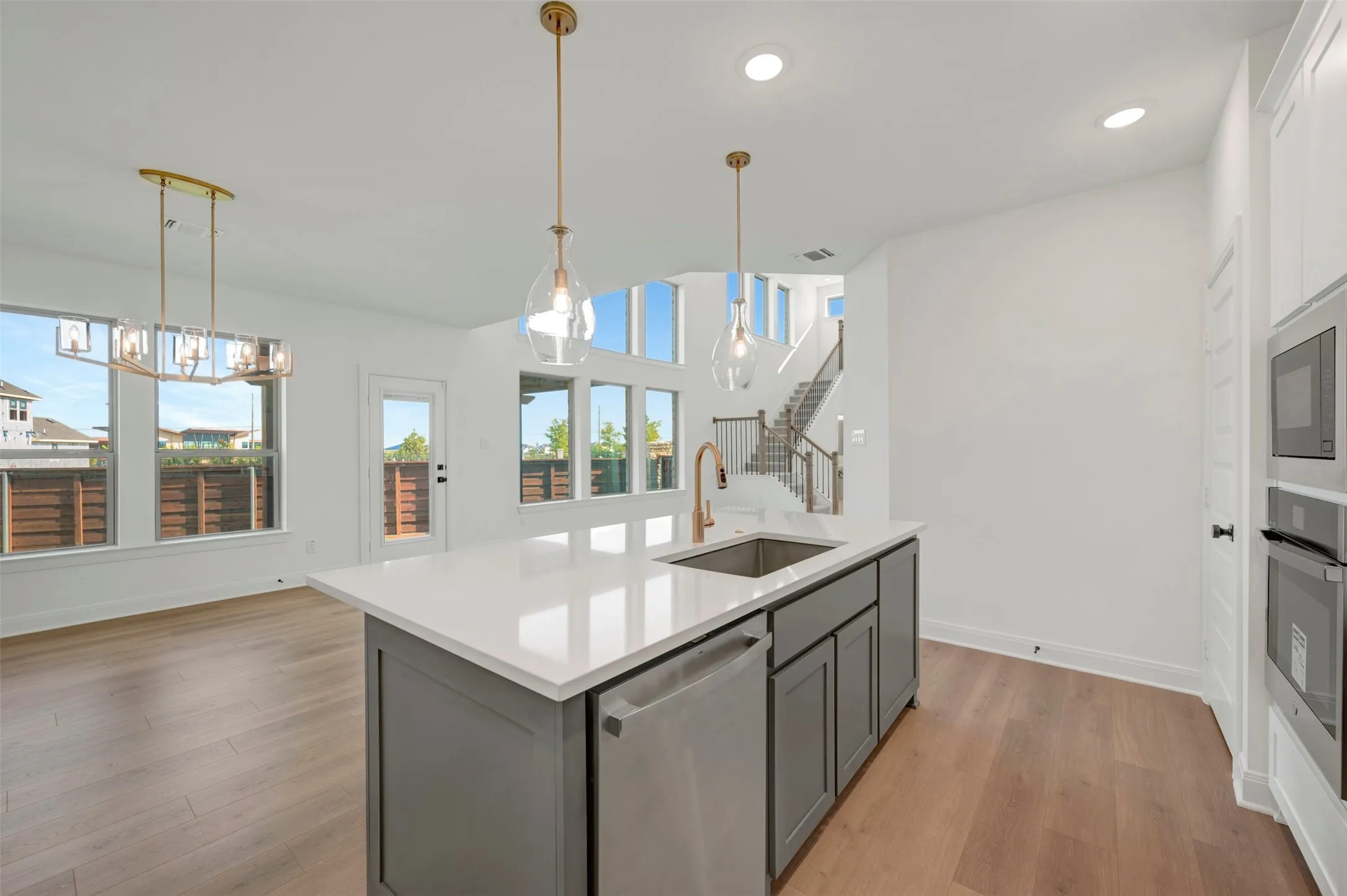 Modern kitchen island featuring a white countertop, undermount sink with a gold-tone faucet, and gray cabinetry