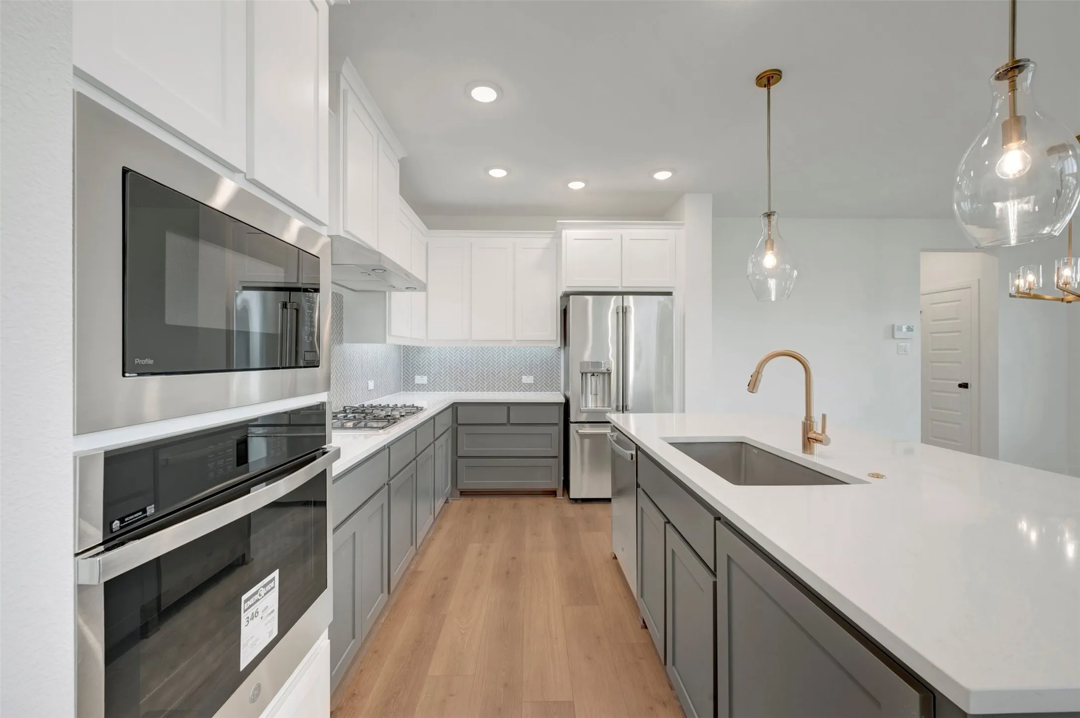 Modern kitchen featuring two-tone cabinetry, stainless steel appliances, and wood-finish flooring