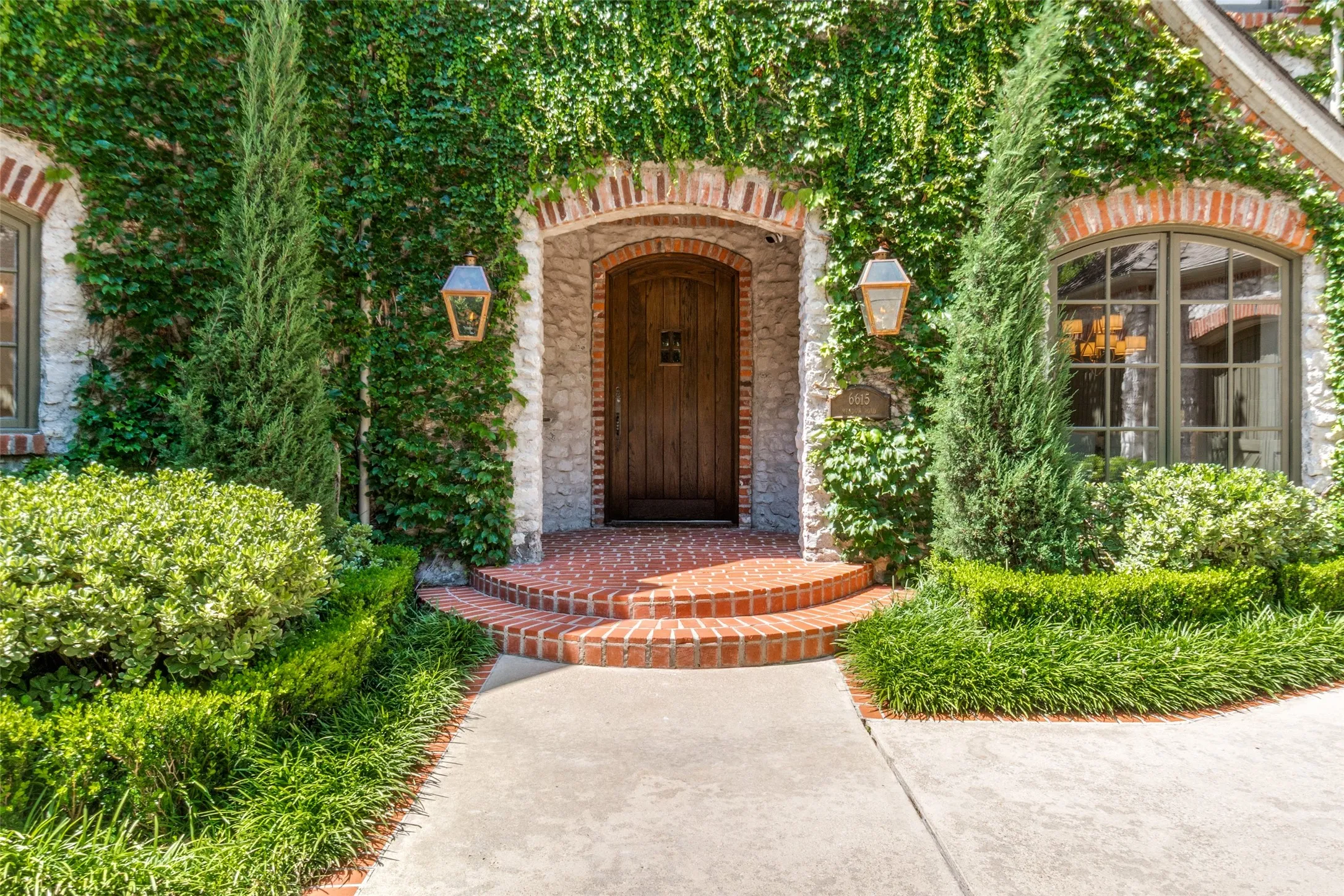 Manicured ivy exterior with copper gas lanterns greet guests to the updated European transitional interiors of 6615 Meadow Rd. An incomparable drive up, reminiscent to the estates found on the East Coast.