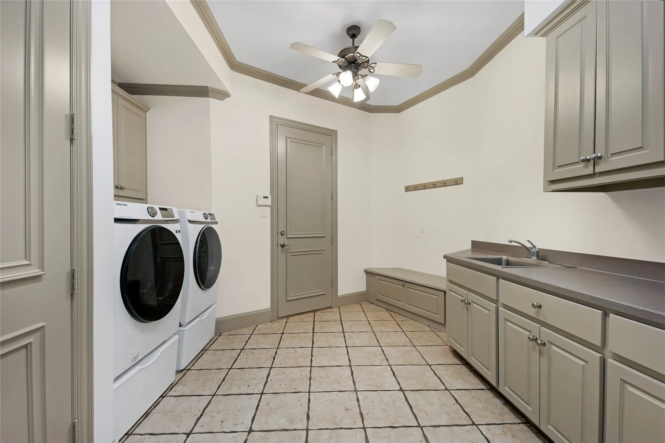 Large laundry room with hidden laundry chute next to the sink. A closet utilizes ample storage under the back stairs, sports shoes and equipment can be put away in the storage bench and coat rack above for backpacks.