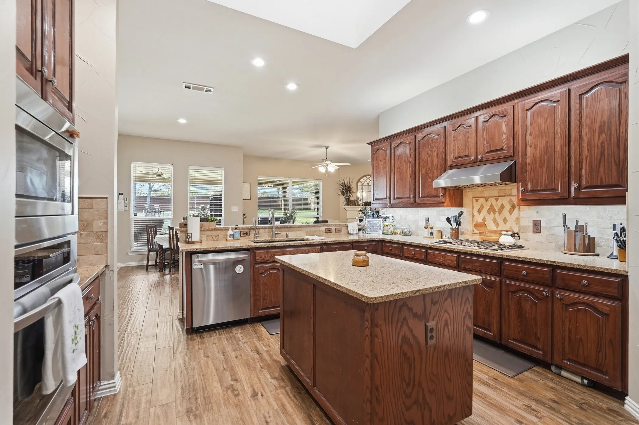Kitchen with a peninsula, light stone countertops, light wood finished floors, and recessed lighting