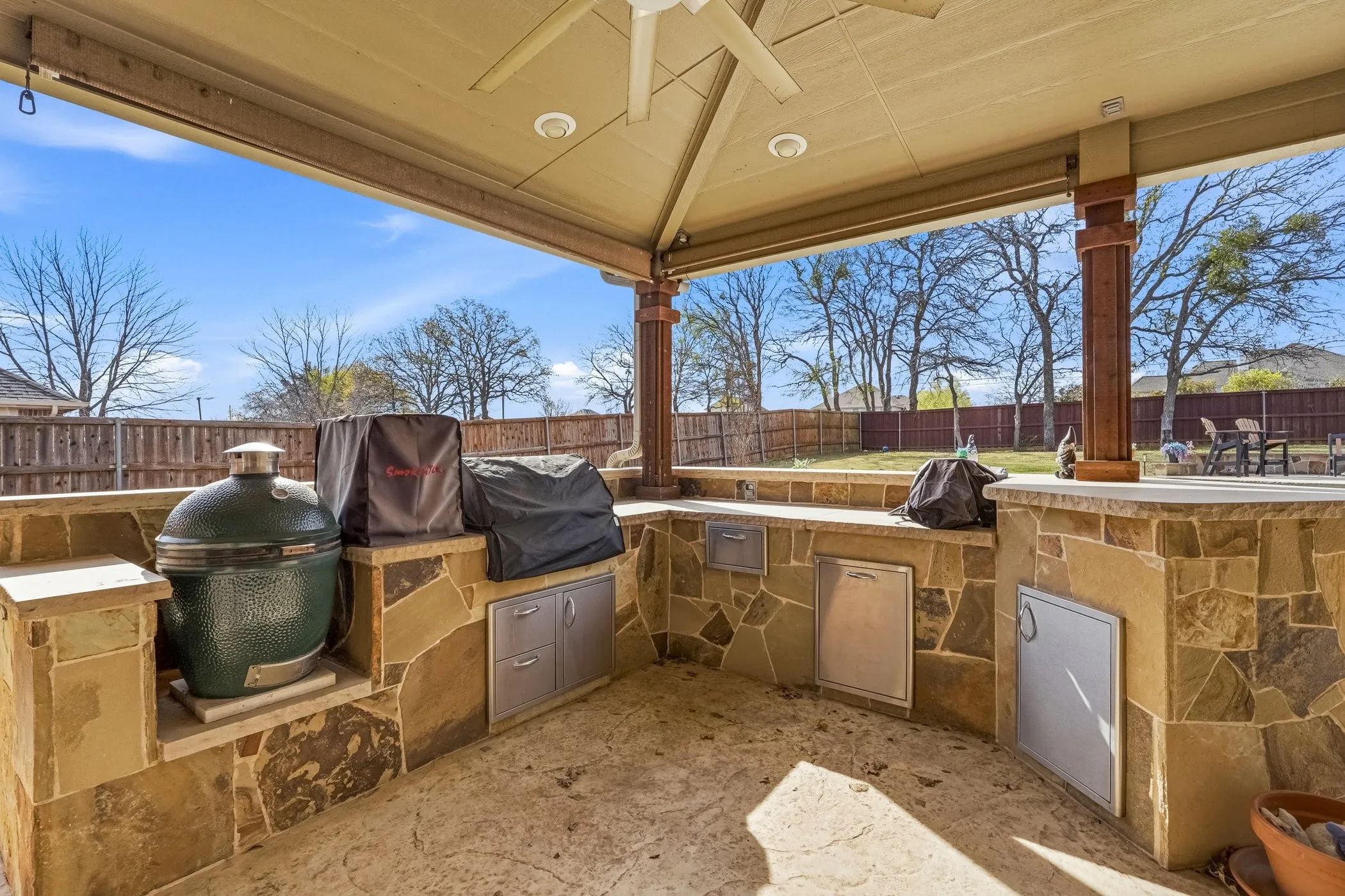 Fenced backyard featuring exterior kitchen, a patio area, and a ceiling fan