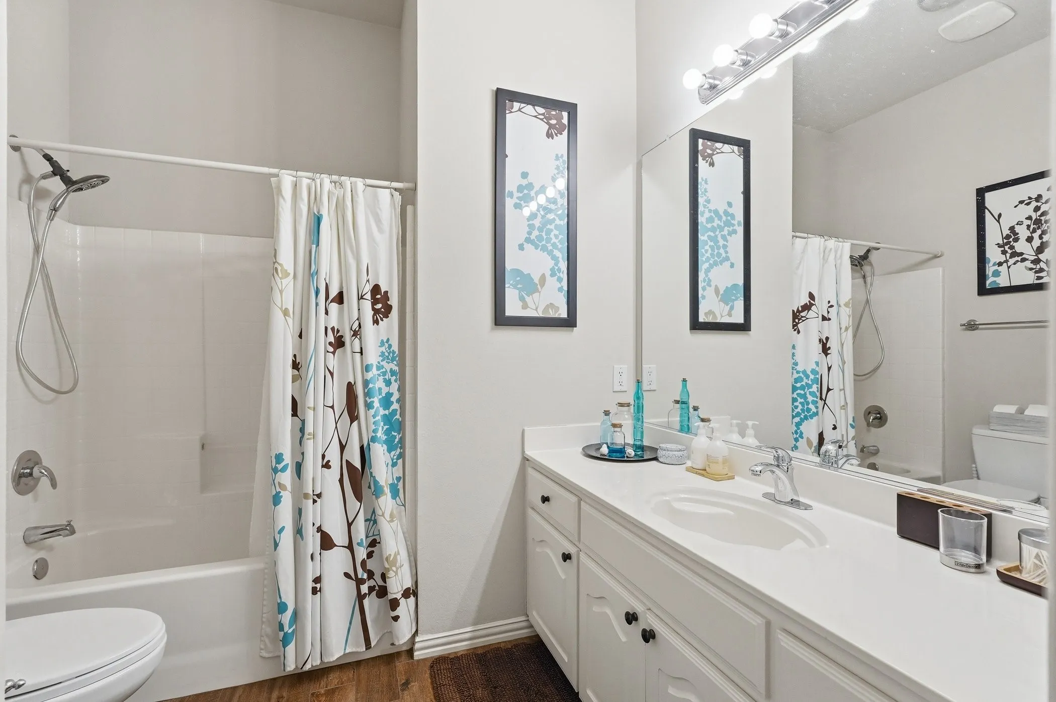 Bathroom featuring shower / bath combination with curtain, vanity, and dark wood-type flooring