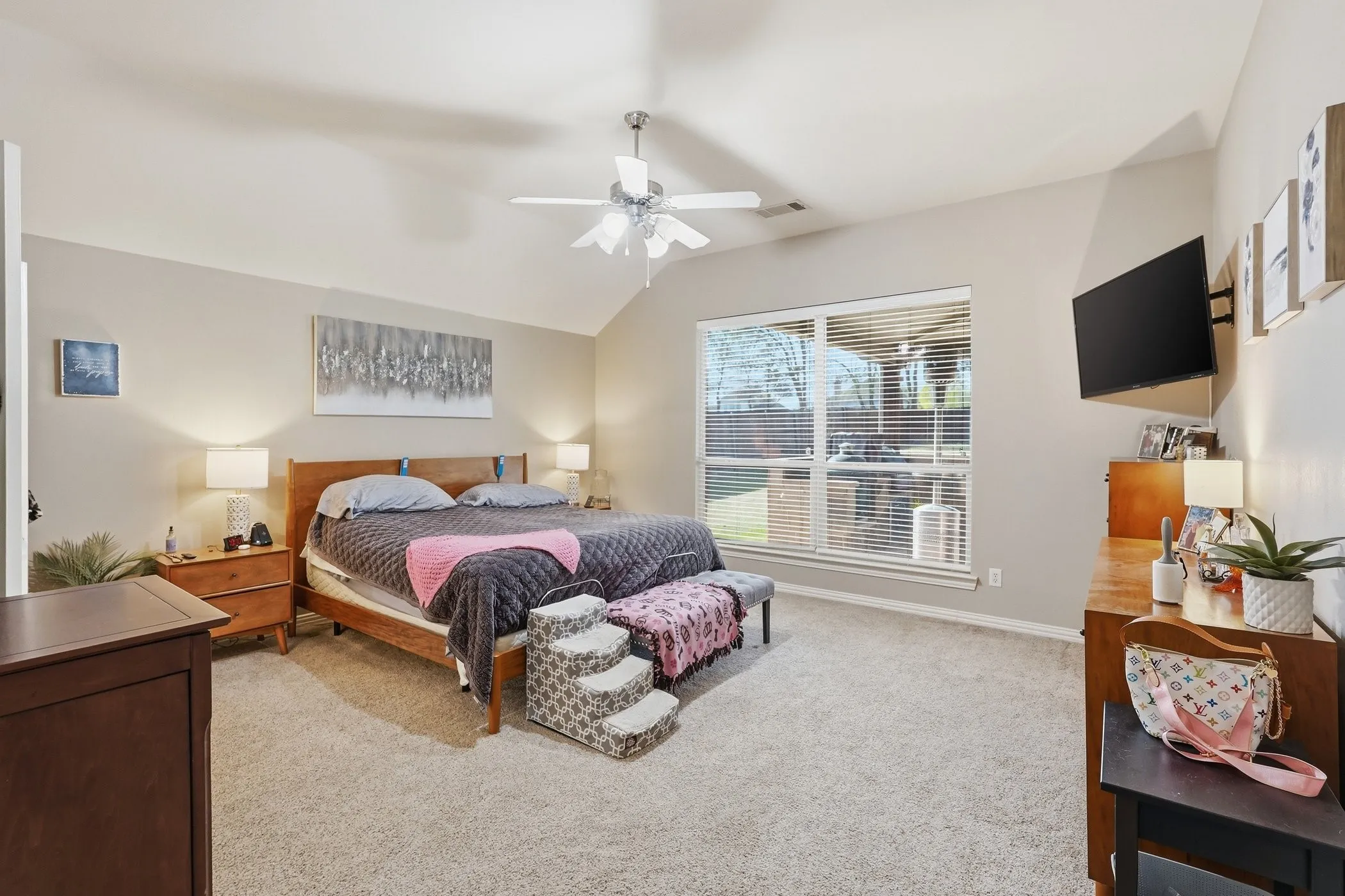 Bedroom featuring light colored carpet, lofted ceiling, and a ceiling fan