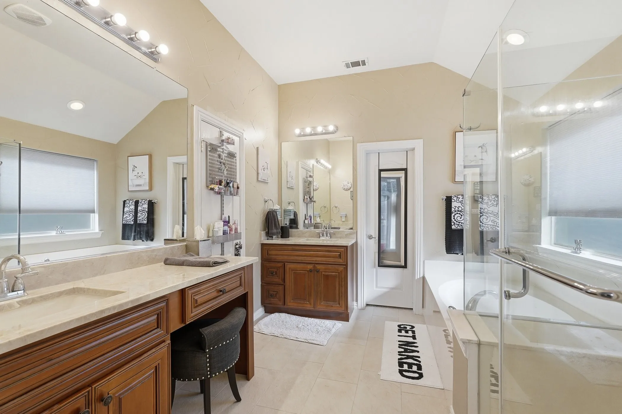 Full bath with a bath, lofted ceiling, a stall shower, two vanities, and light tile patterned floors