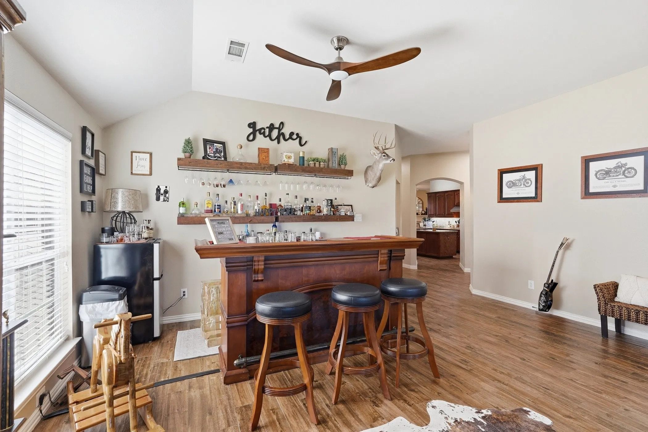 Indoor dry bar with a ceiling fan, freestanding refrigerator, arched walkways, light wood-type flooring, and open shelves