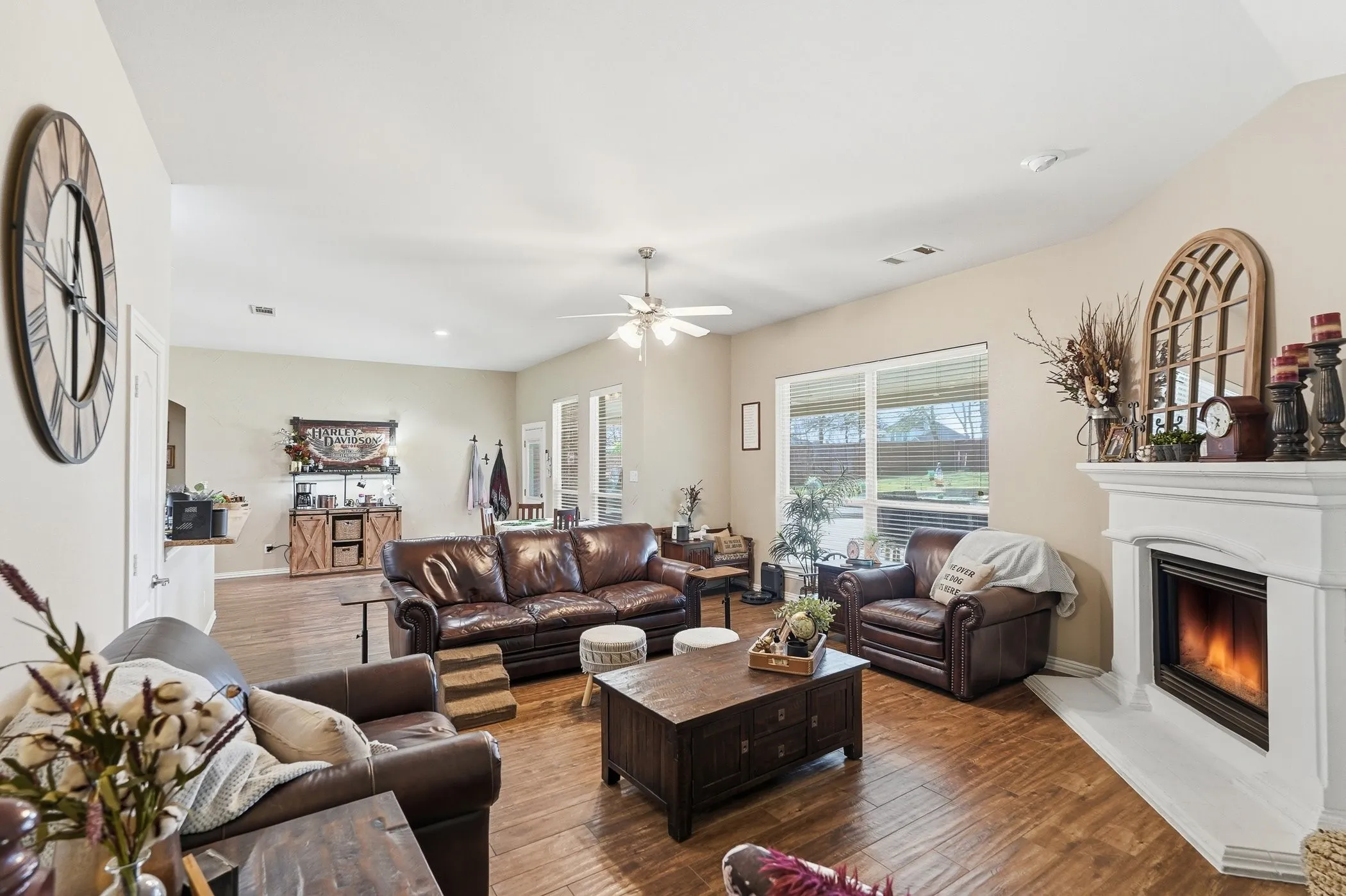 Living room featuring hardwood / wood-style flooring, a ceiling fan, and a glass covered fireplace